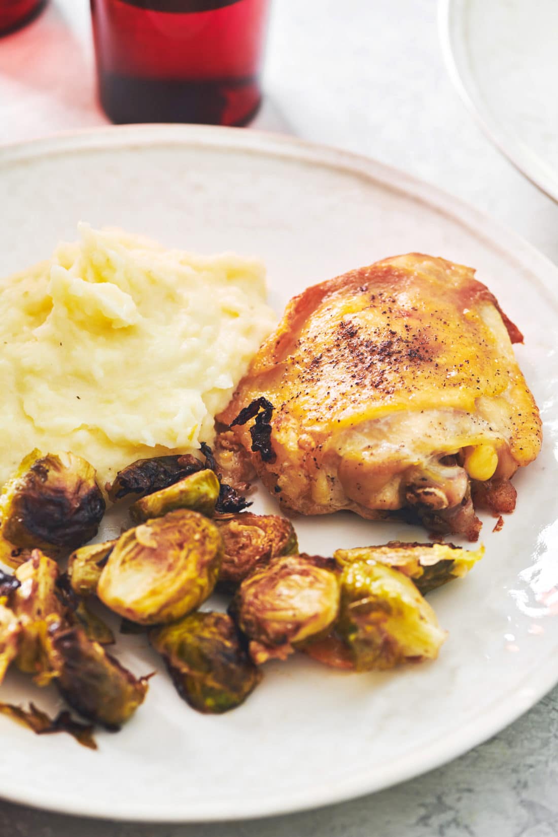 Mashed Potatoes with Parmesan cheese on a plate with roasted chicken and brussels sprouts