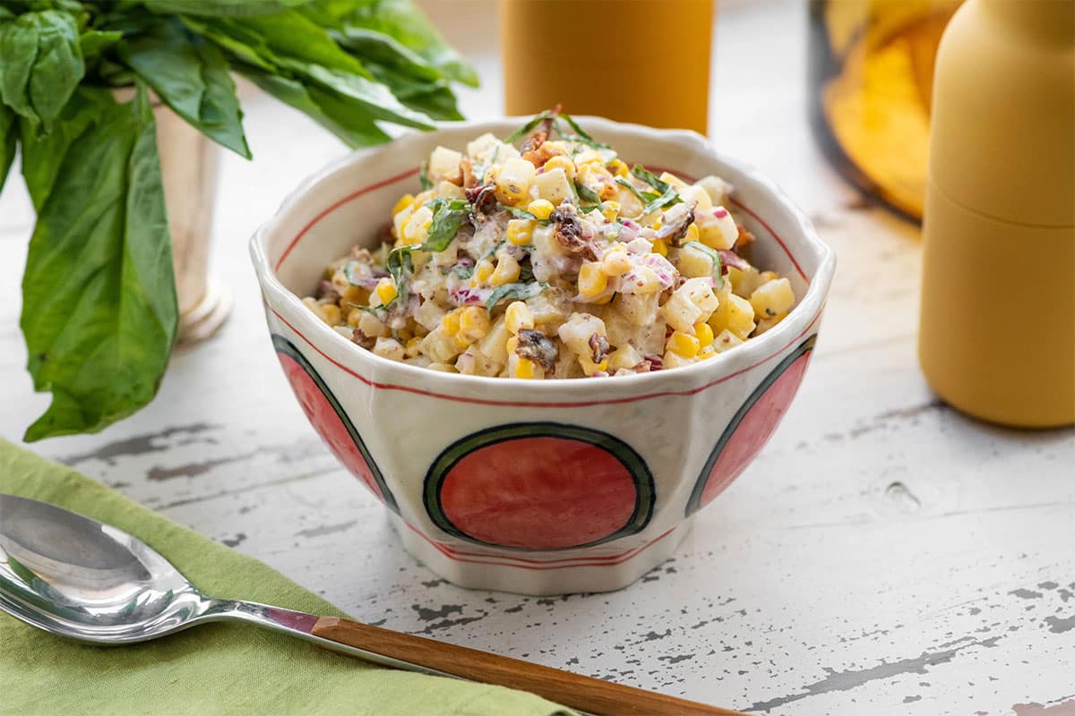 Decorated bowl of Creamy Corn and Potato Salad with Bacon and Lemon Buttermilk Dressing.