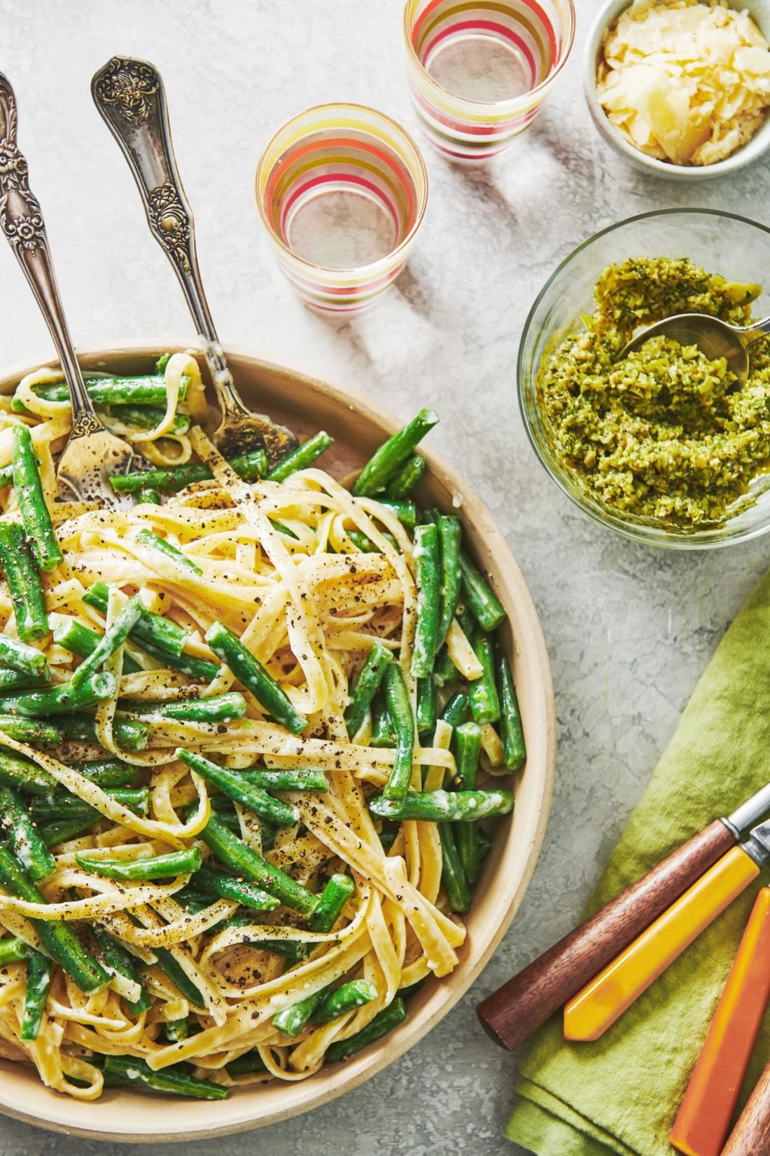 Bowl of Spring Fettuccine Alfredo with Green Beans and Tapenade with two spoons.