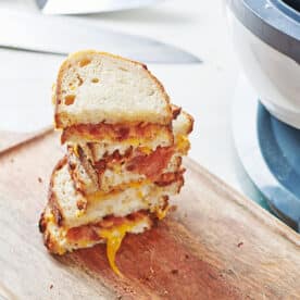 Stack of grilled cheese sandwiches near air fryer.