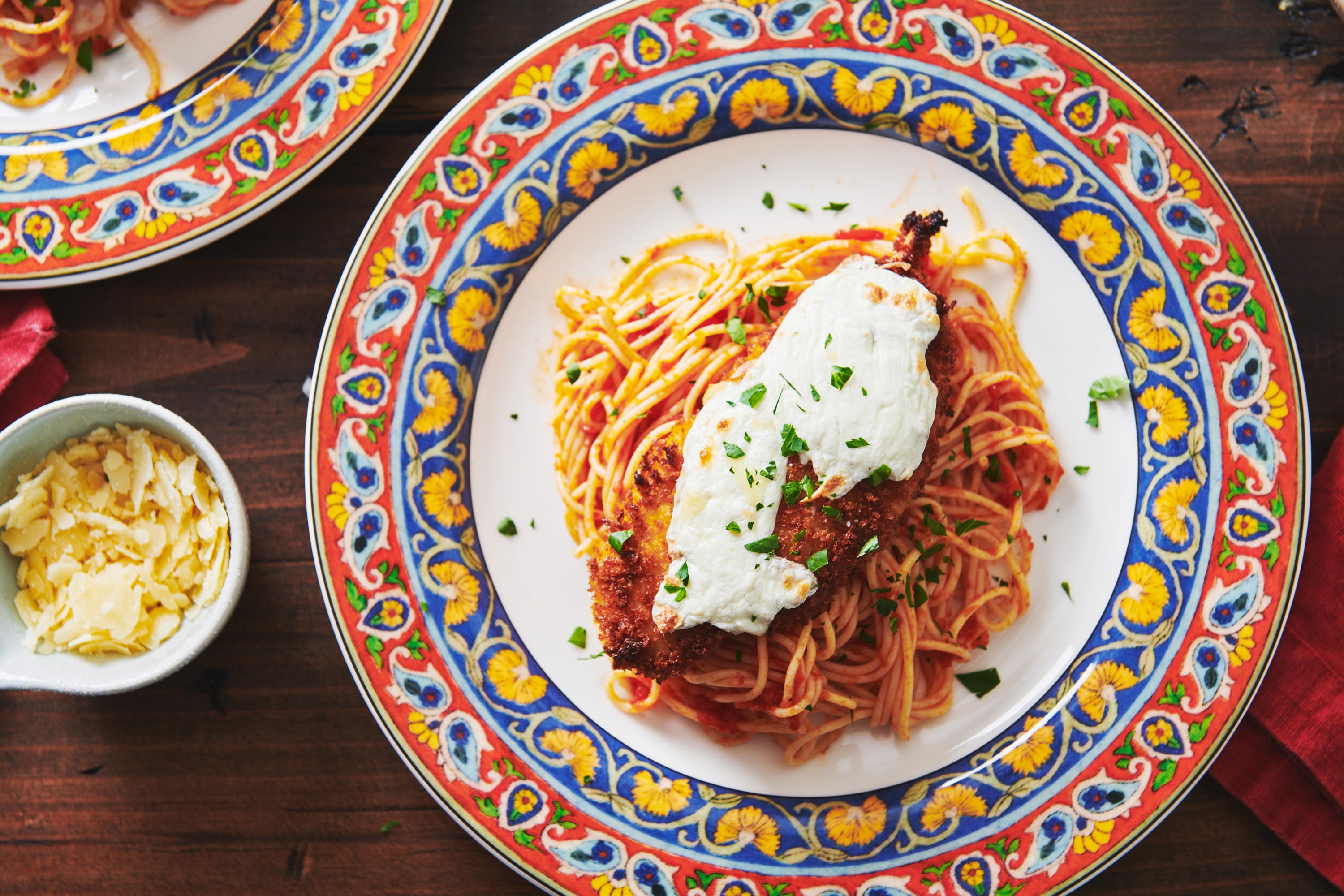 Chicken Parmigiana with spaghetti on a plate with a colorful border.