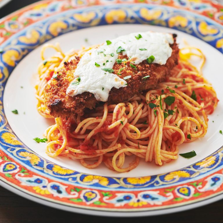 Chicken Parmigiana with spaghetti on colorful plate.