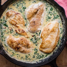 Creamy Spinach, Sundried Tomato and Garlic Chicken in cast-iron skillet on table.