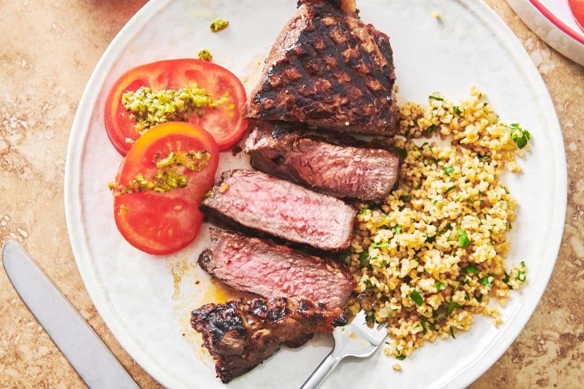 Grains, tomatoes, and Grilled Marinated NY Strip Steak on a plate.