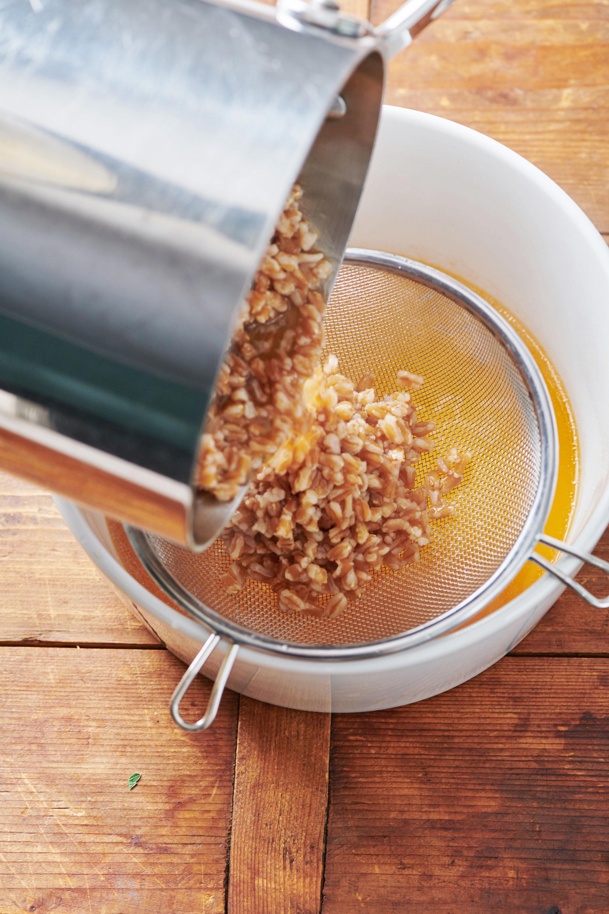 Cooked farro being drained in a sieve.