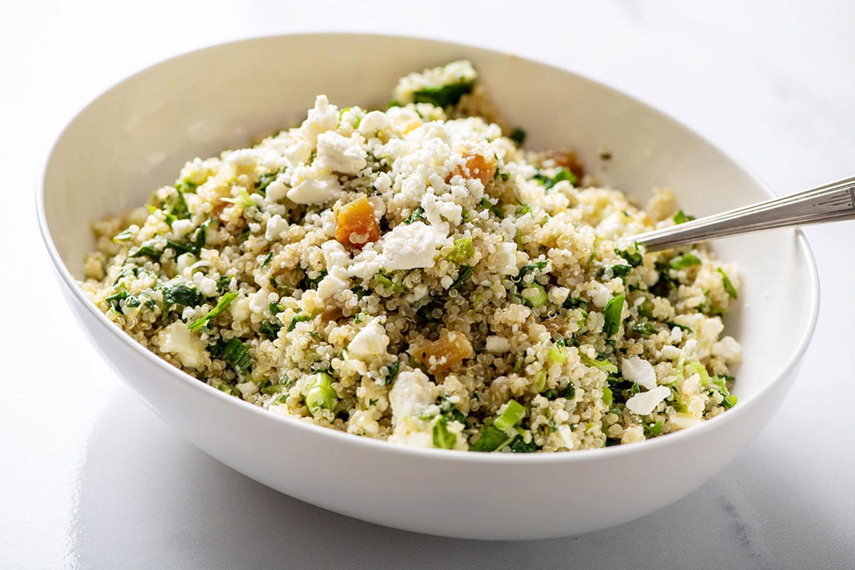 Kale Quinoa Salad with Honey, Lemon and Dijon Dressing in large white serving dish with spoon.