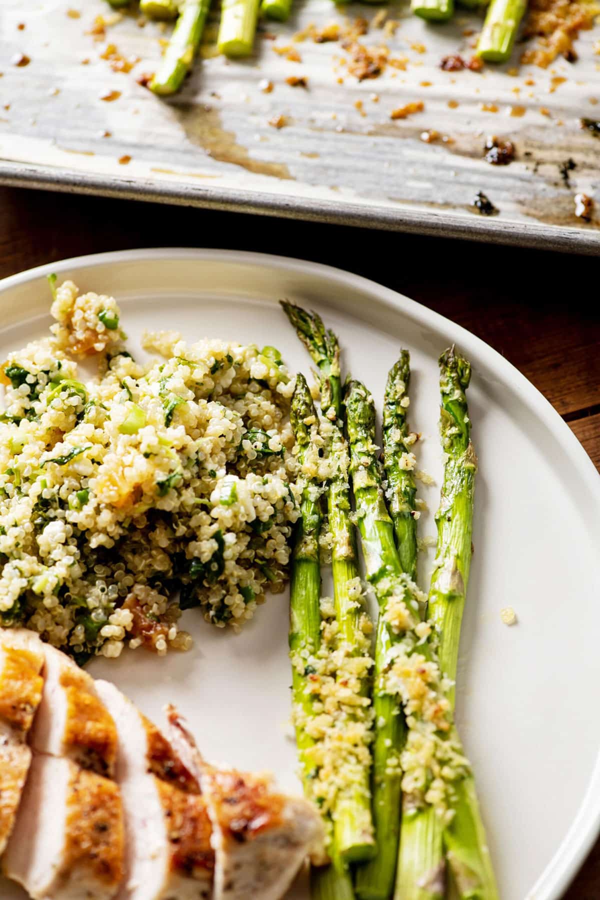 Kale Quinoa Salad on plate with asparagus and sliced chicken.