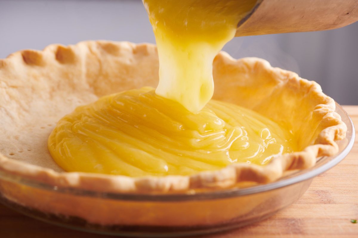 pouring lemon curd into a pie shell