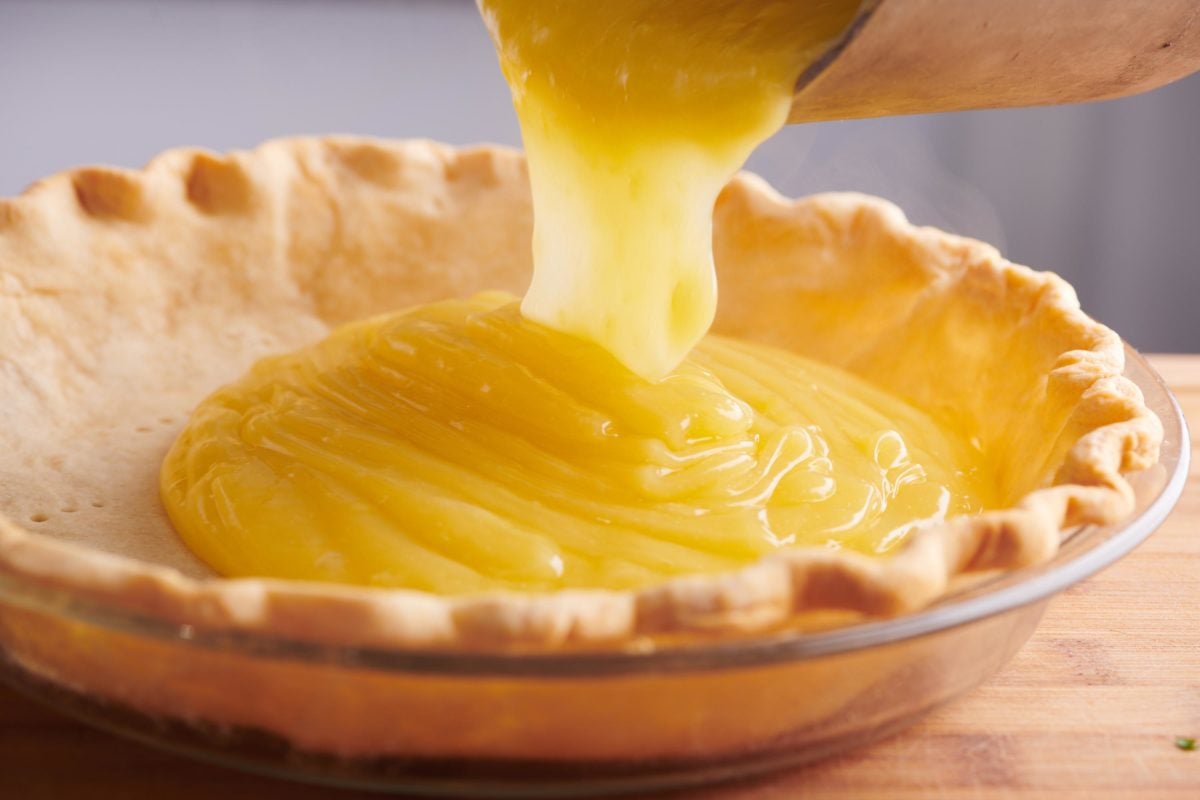 pouring lemon curd into a pie shell