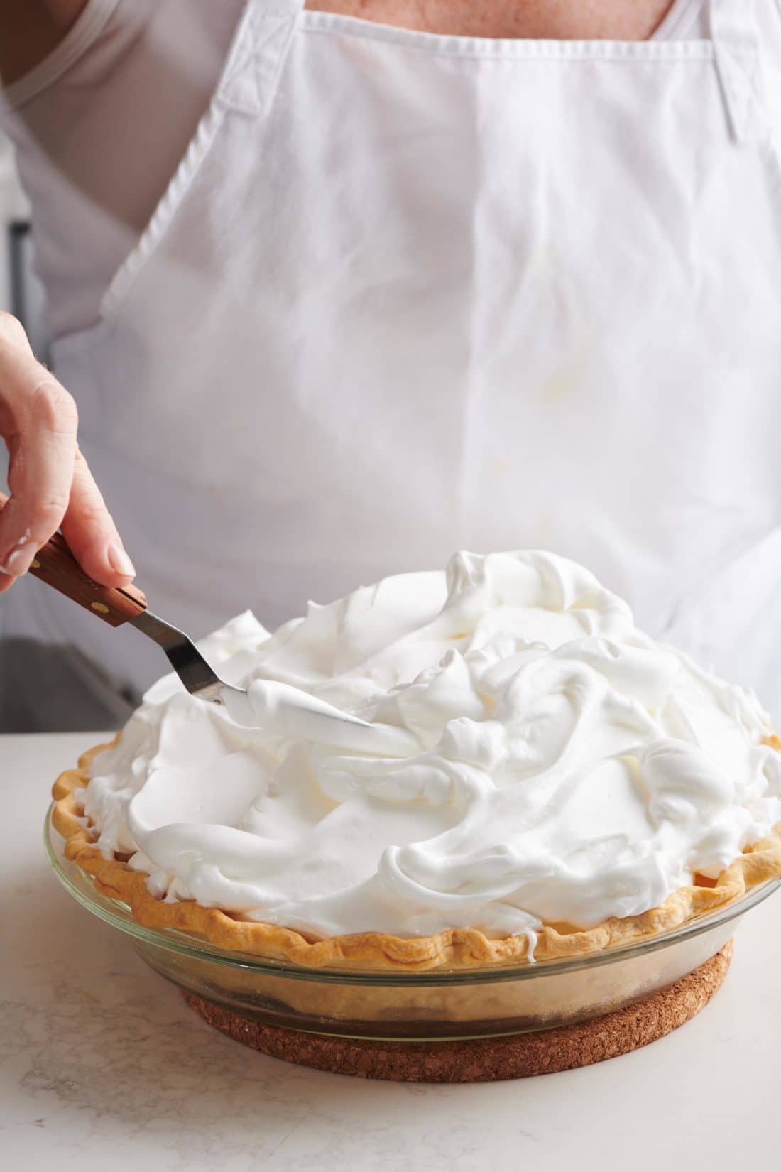spreading meringue on a pie with an offset spatula