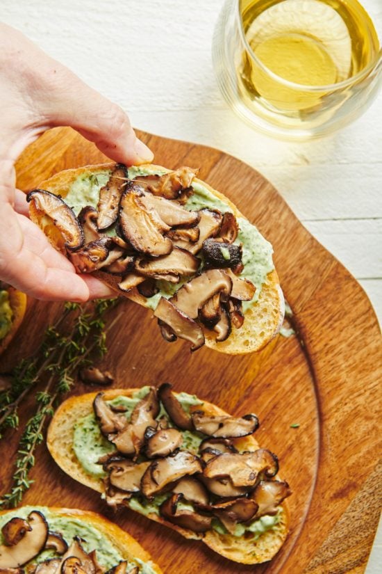 Woman grabbing a Mushroom Bruschetta with Herbed Mayonnaise.