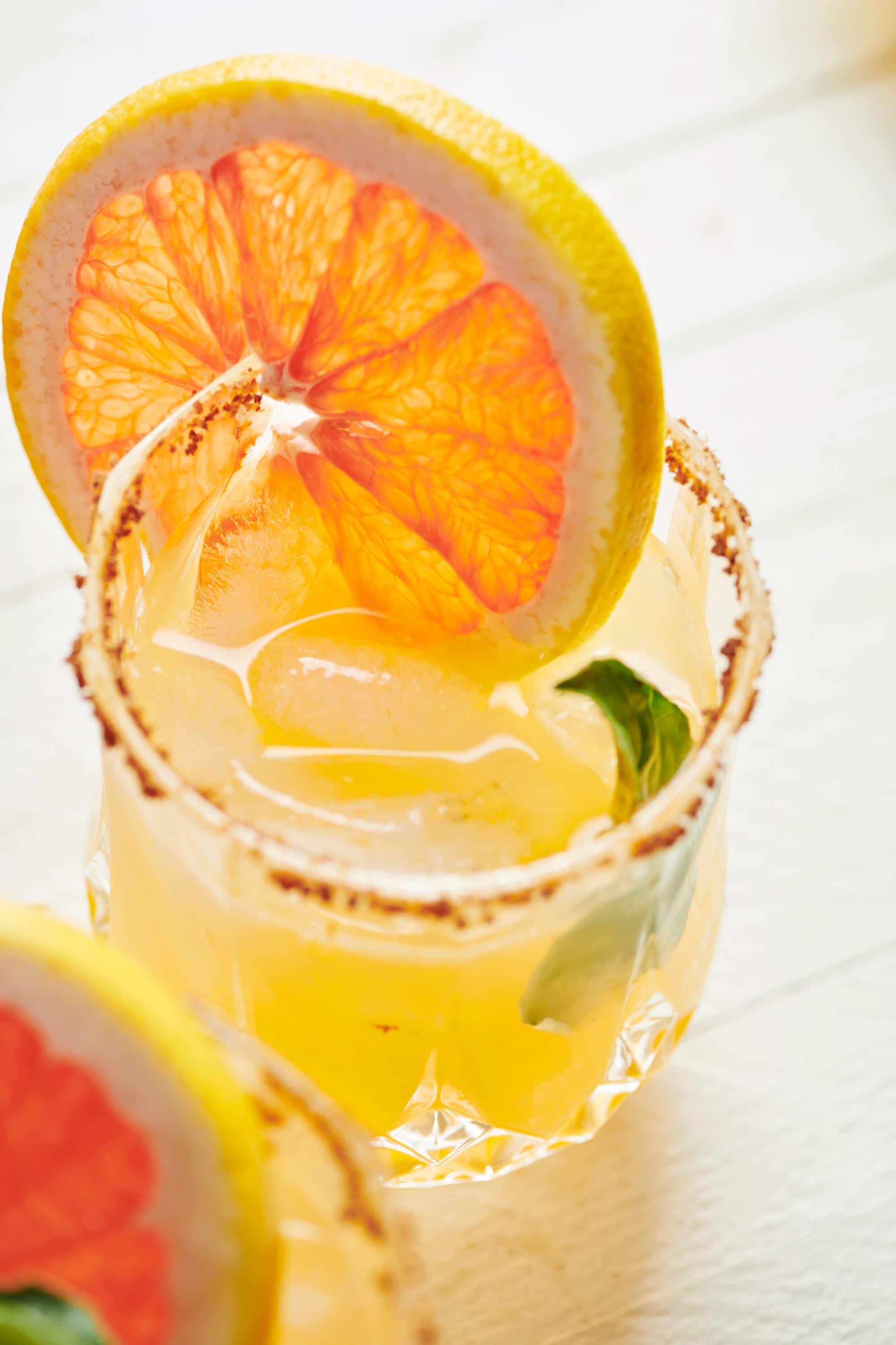 Pomelo and yuzu paloma cocktail in rocks glass with citrus garnish.