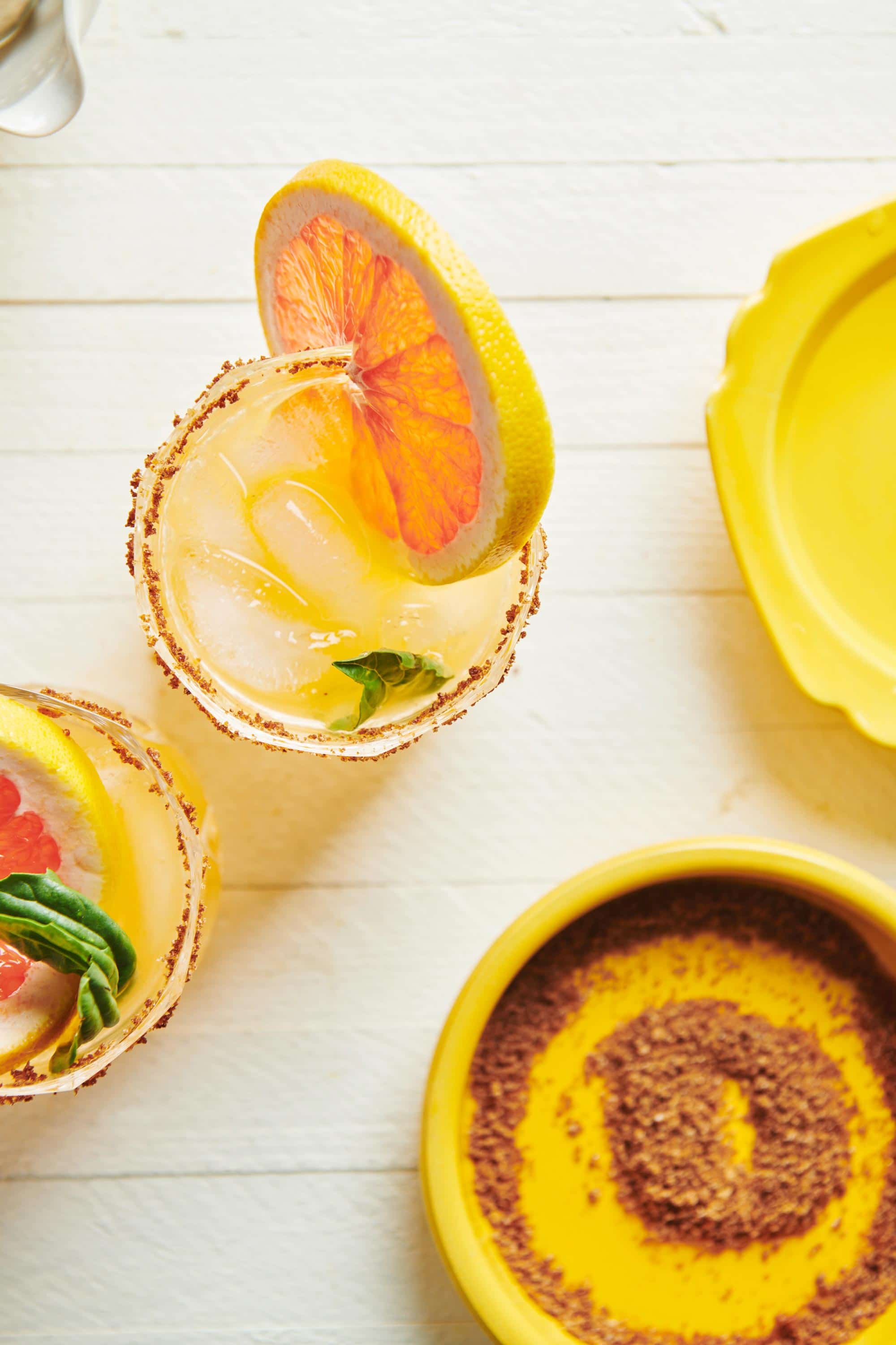 Two Pomelo Palomas in small glasses with sriracha salt rims.