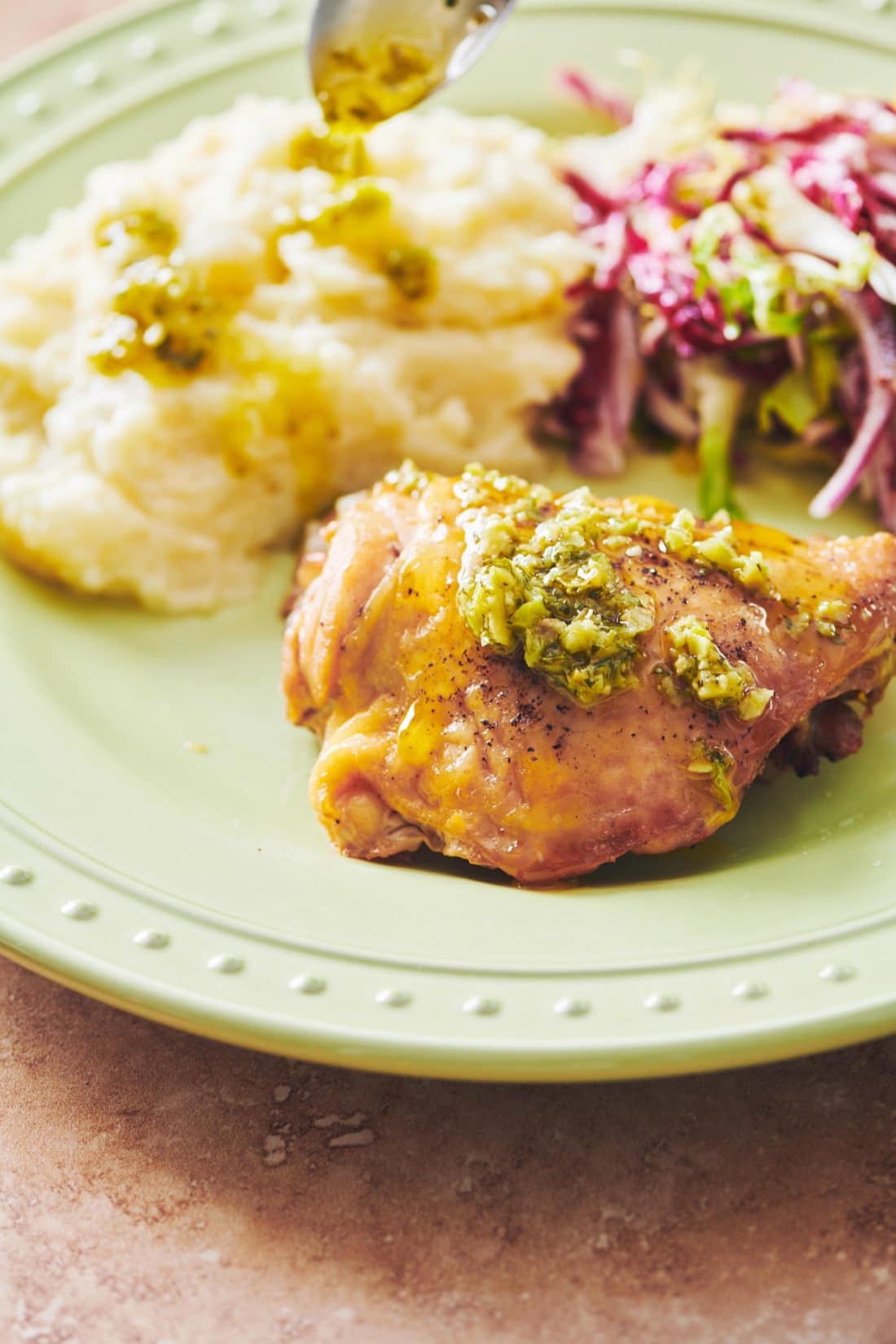 Roasted Chicken Thigh with green olive tapenade on plate.