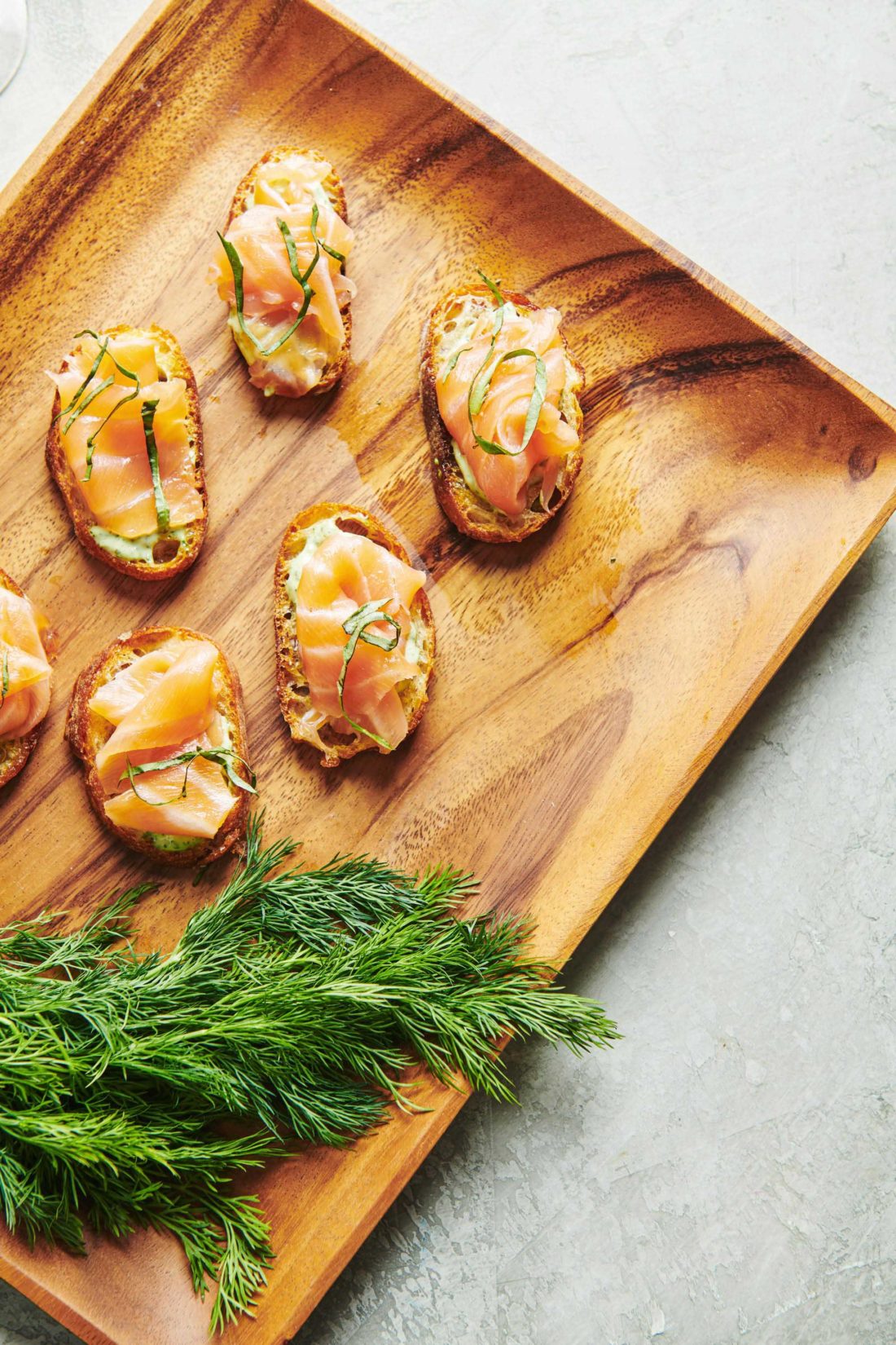 Smoked Salmon Crostini with Herbed Mayonnaise on a wooden tray.