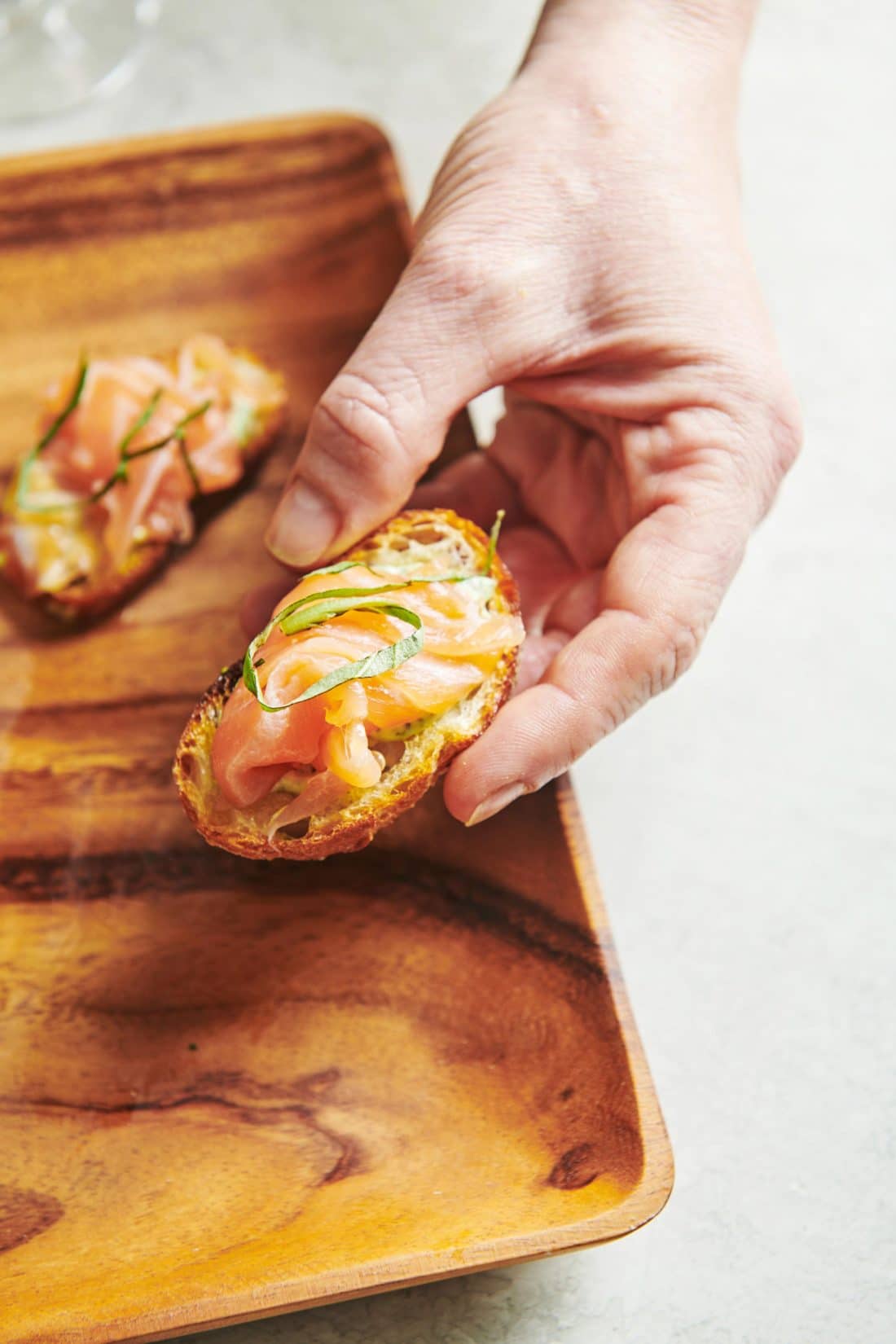 Woman holding a Smoked Salmon Crostini with Herbed Mayonnaise.