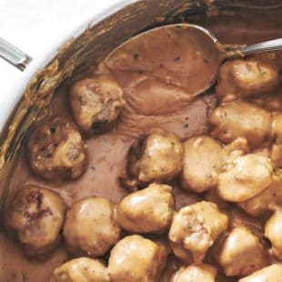 Spoon in a pan of Swedish Meatballs.
