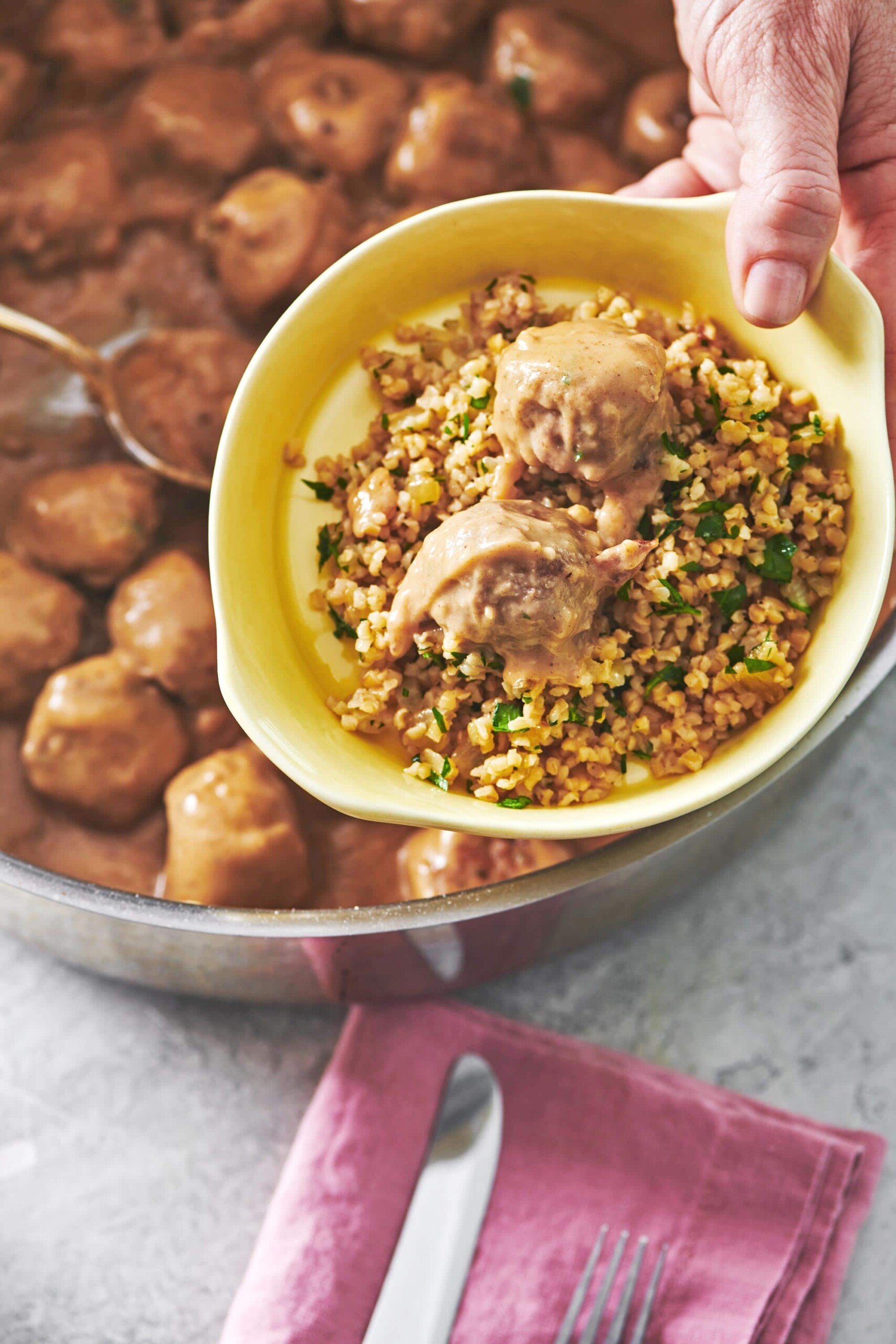 Swedish Meatballs over grains in a yellow bowl.