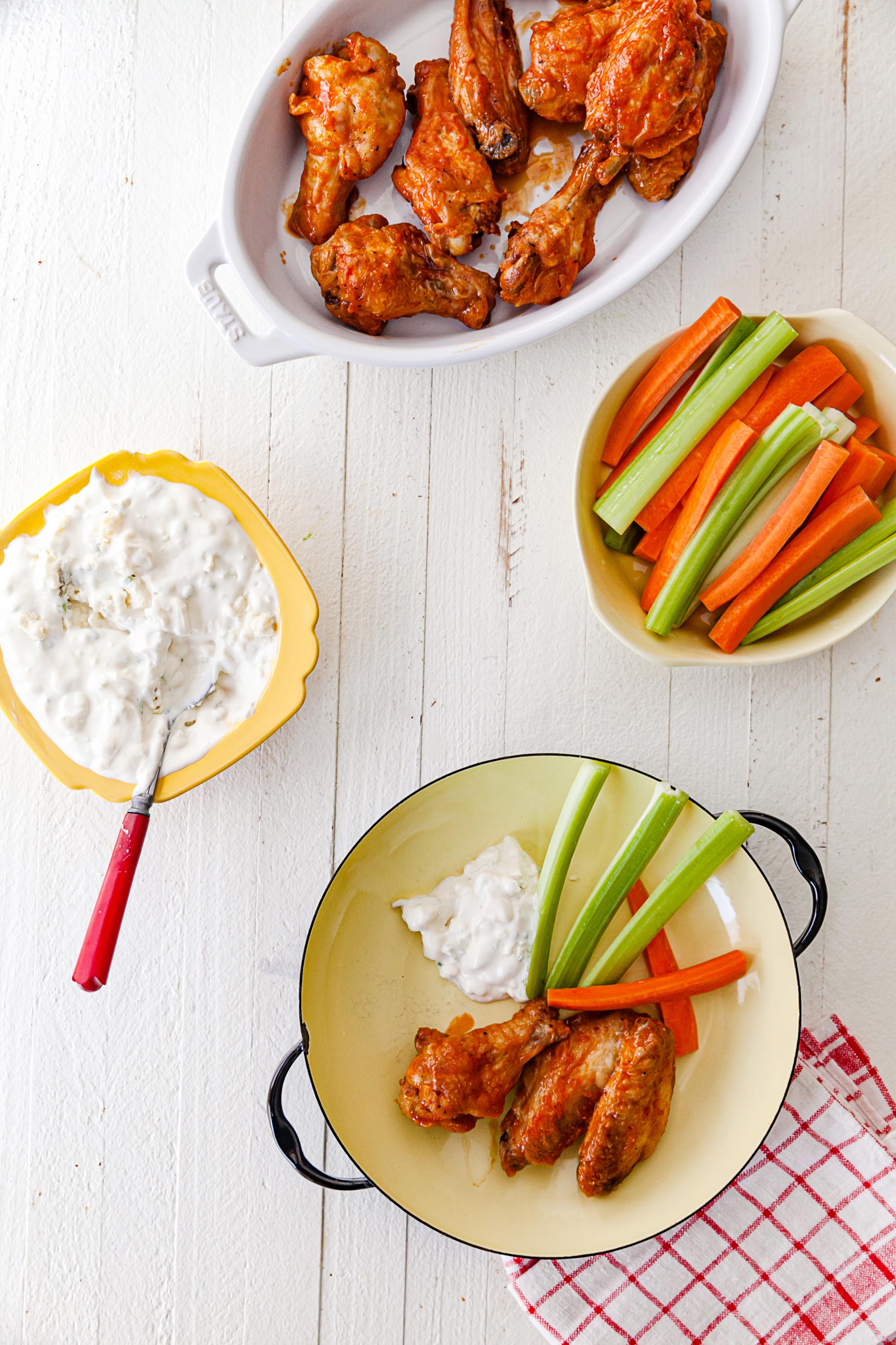 Air Fryer Buffalo Chicken Wings in a serving dish with blue cheese dip and sticks of carrots and celery.