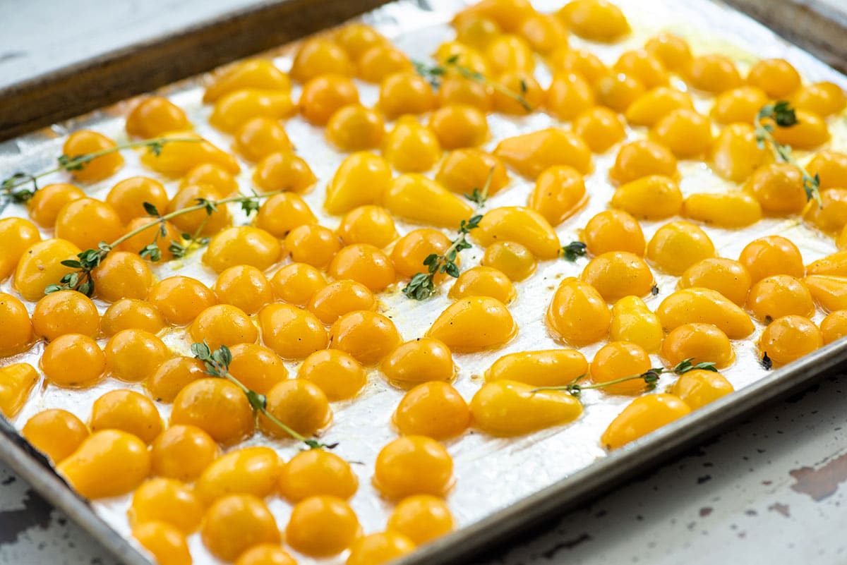 Yellow tomatoes about to be roasted on baking sheet.