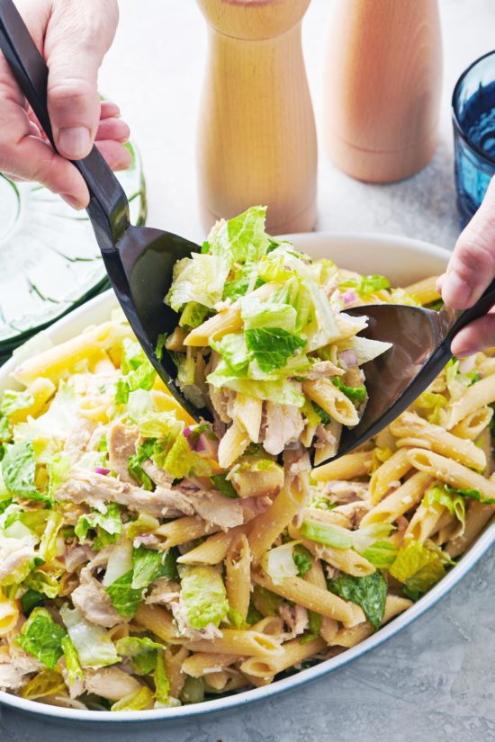 Two spoons scooping Chicken Caesar Pasta Salad.