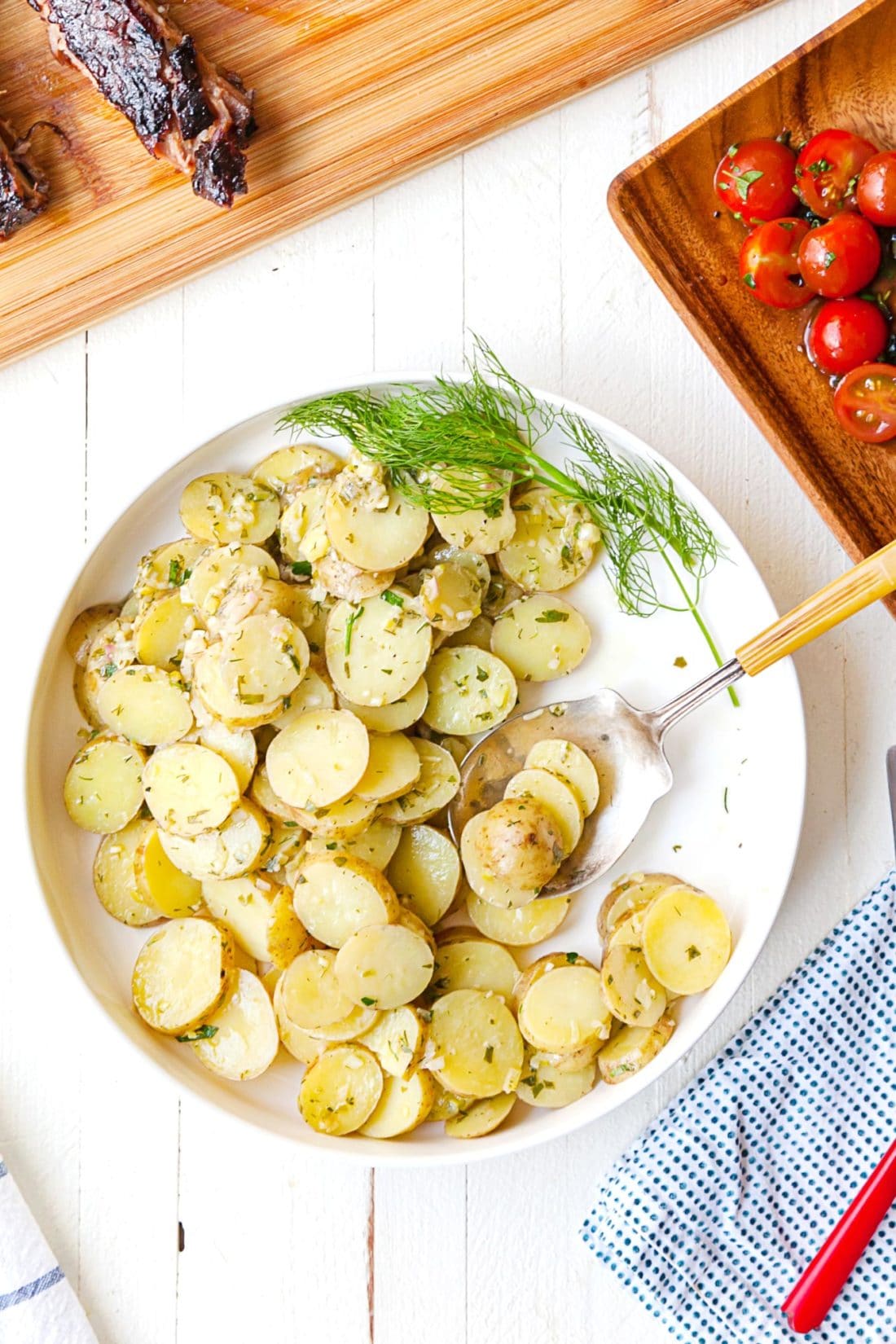 Large white bowl of French Potato Salad with a spoon.