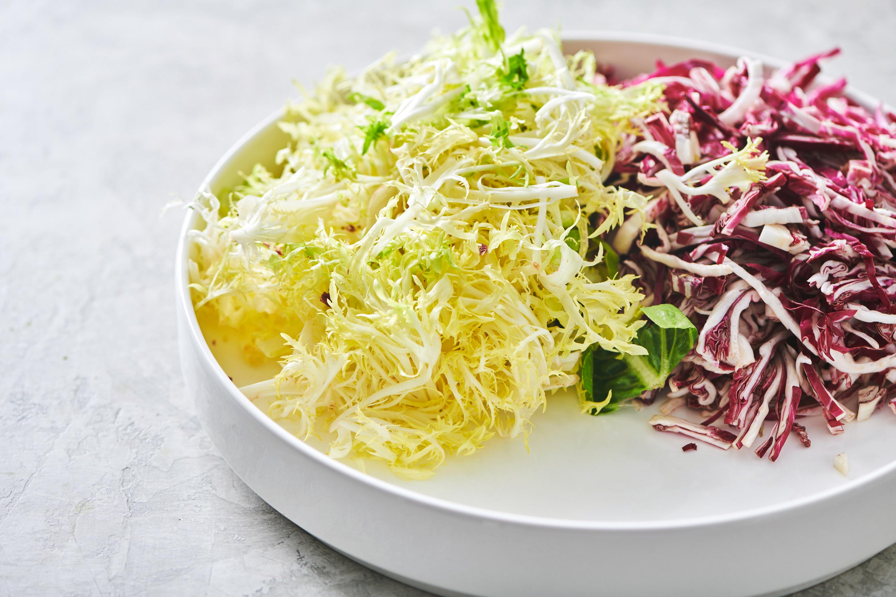 Thinly sliced Frisee lettuce on a plate with radicchio.