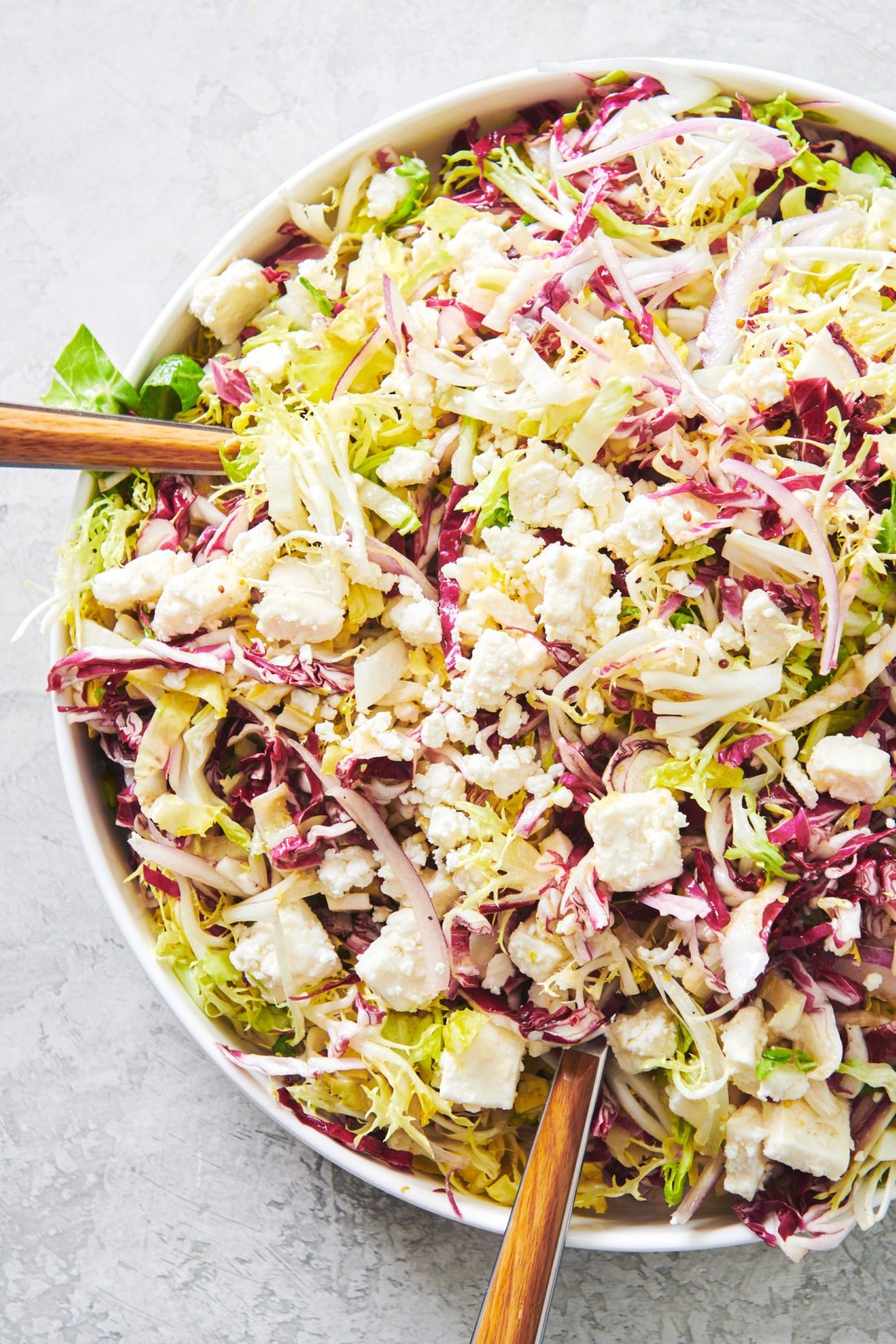 Utensils in a bowl of Frisee, Radicchio and Escarole Salad with Citrus Dressing.