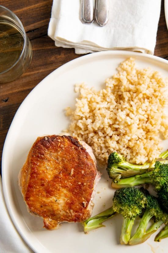 Garlicky Pork Chops and Broccoli with a side of couscous on white plate
