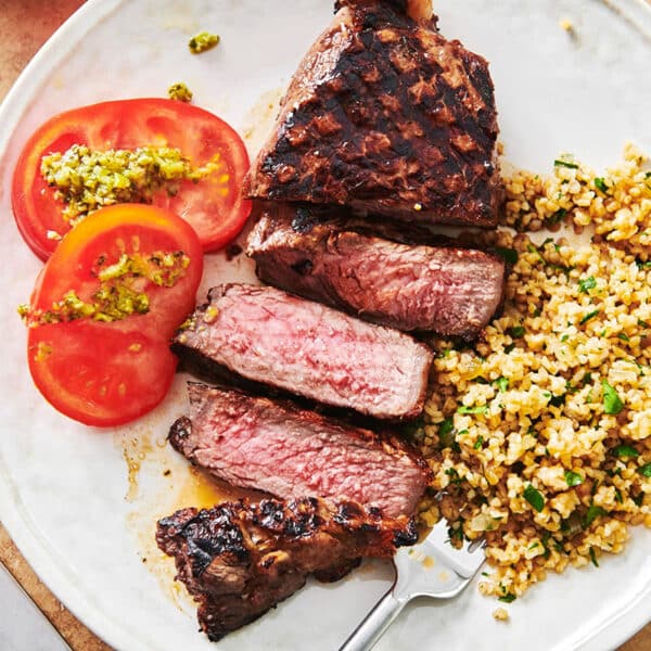 Grains, tomatoes, and Grilled Marinated NY Strip Steak on a plate.