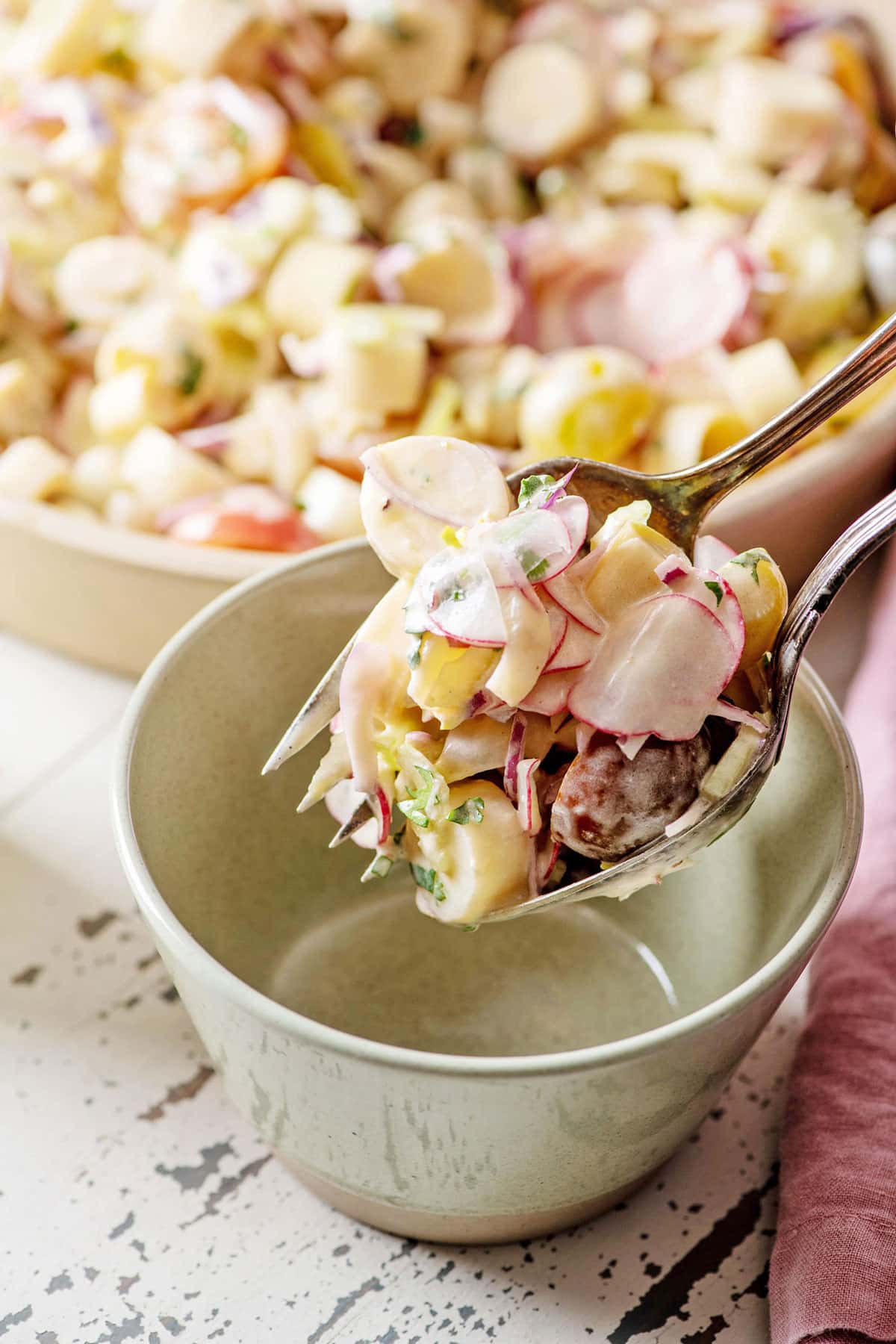Scooping a portion of Hearts of Palm Salad with spoon and fork in a bowl.