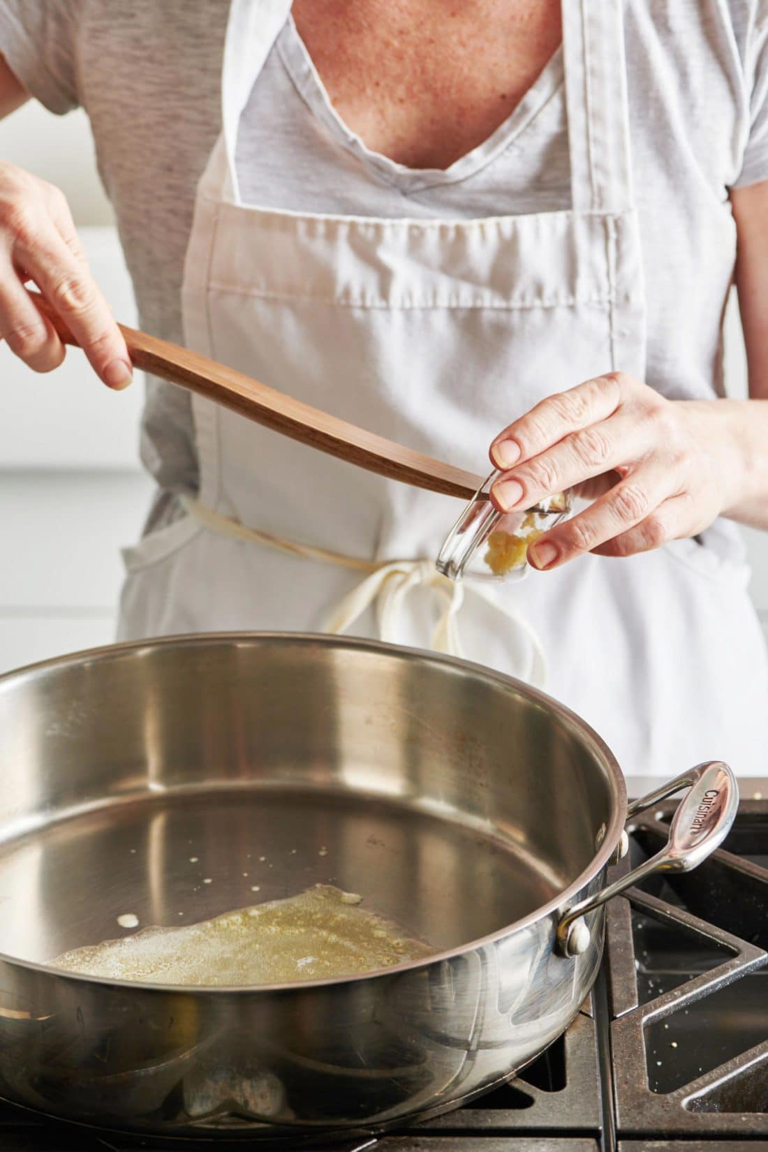Woman adding garlic to a pan with oil.