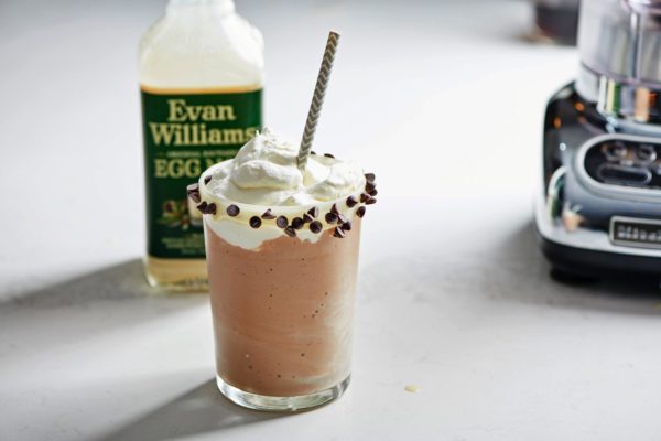 Egg Nog milkshake in a glass with a white chocolate and chocolate chip rim.