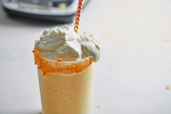 Orange straw in a glass of mango egg nog milkshake.