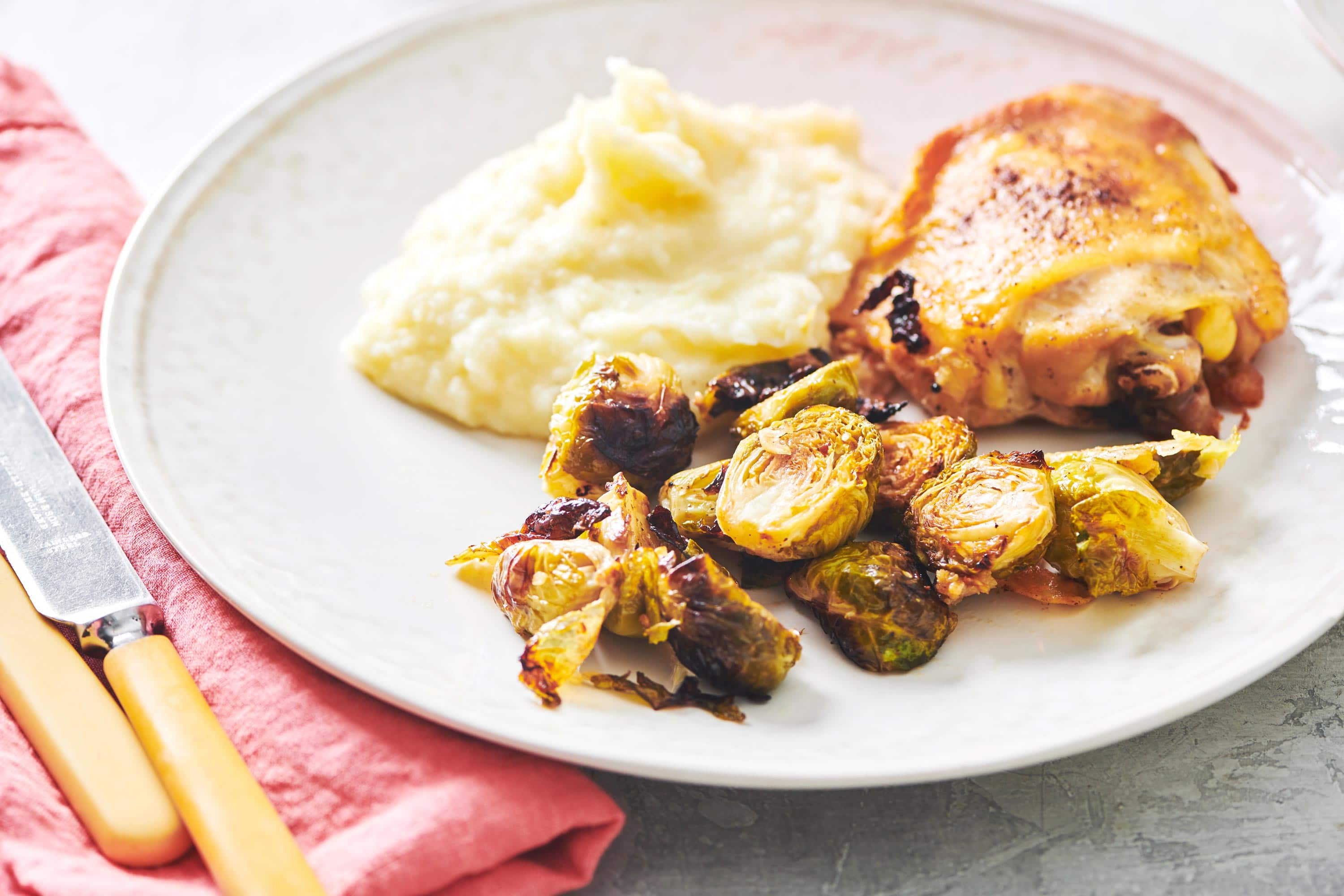 Parmesan Roasted Brussels Sprouts on a plate with chicken and mashed potatoes.