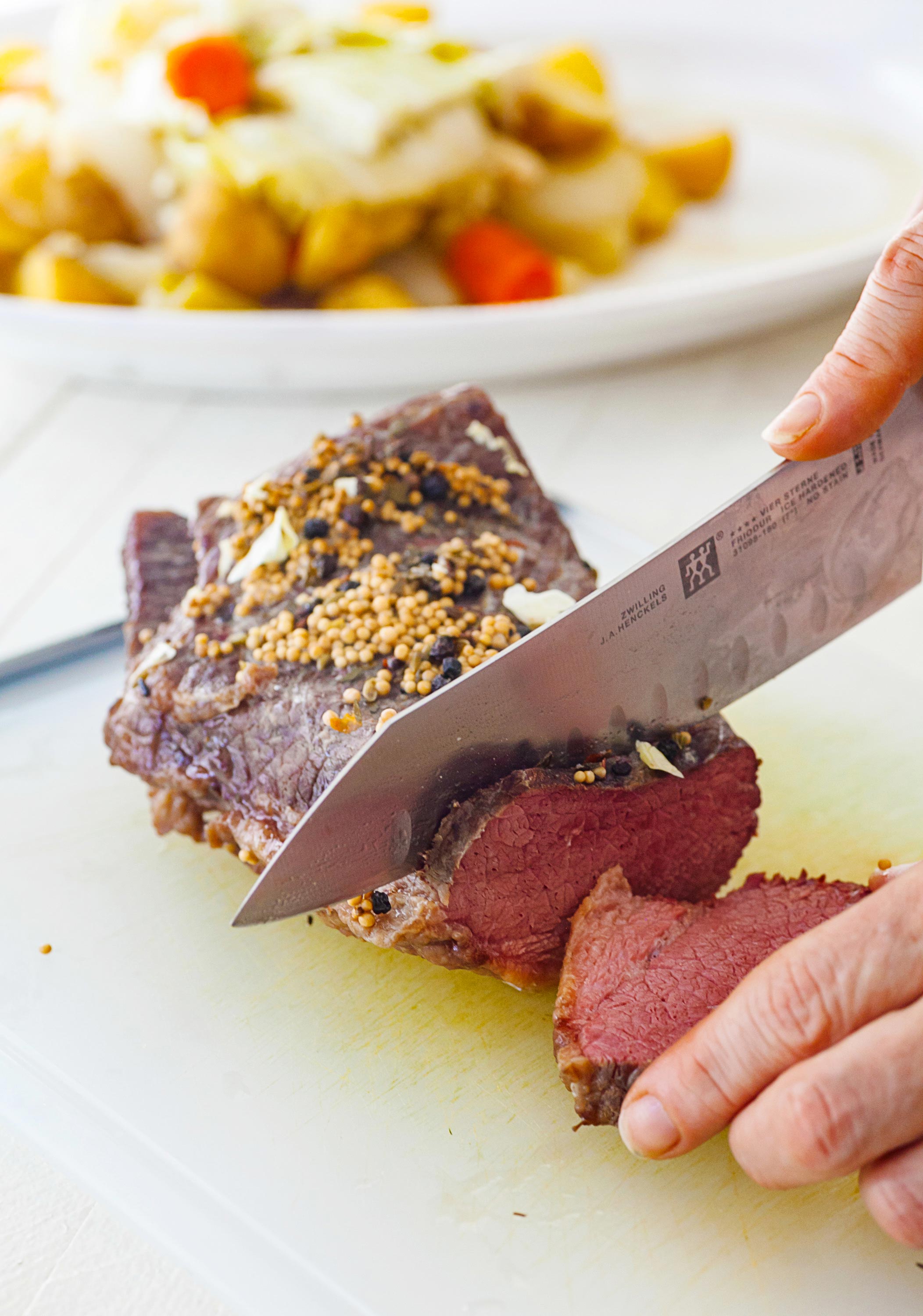 Woman slicing corned beef on a cutting board.