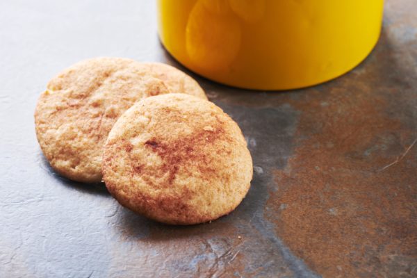 Snickerdoodles on a counter next to a yellow cookie jar.