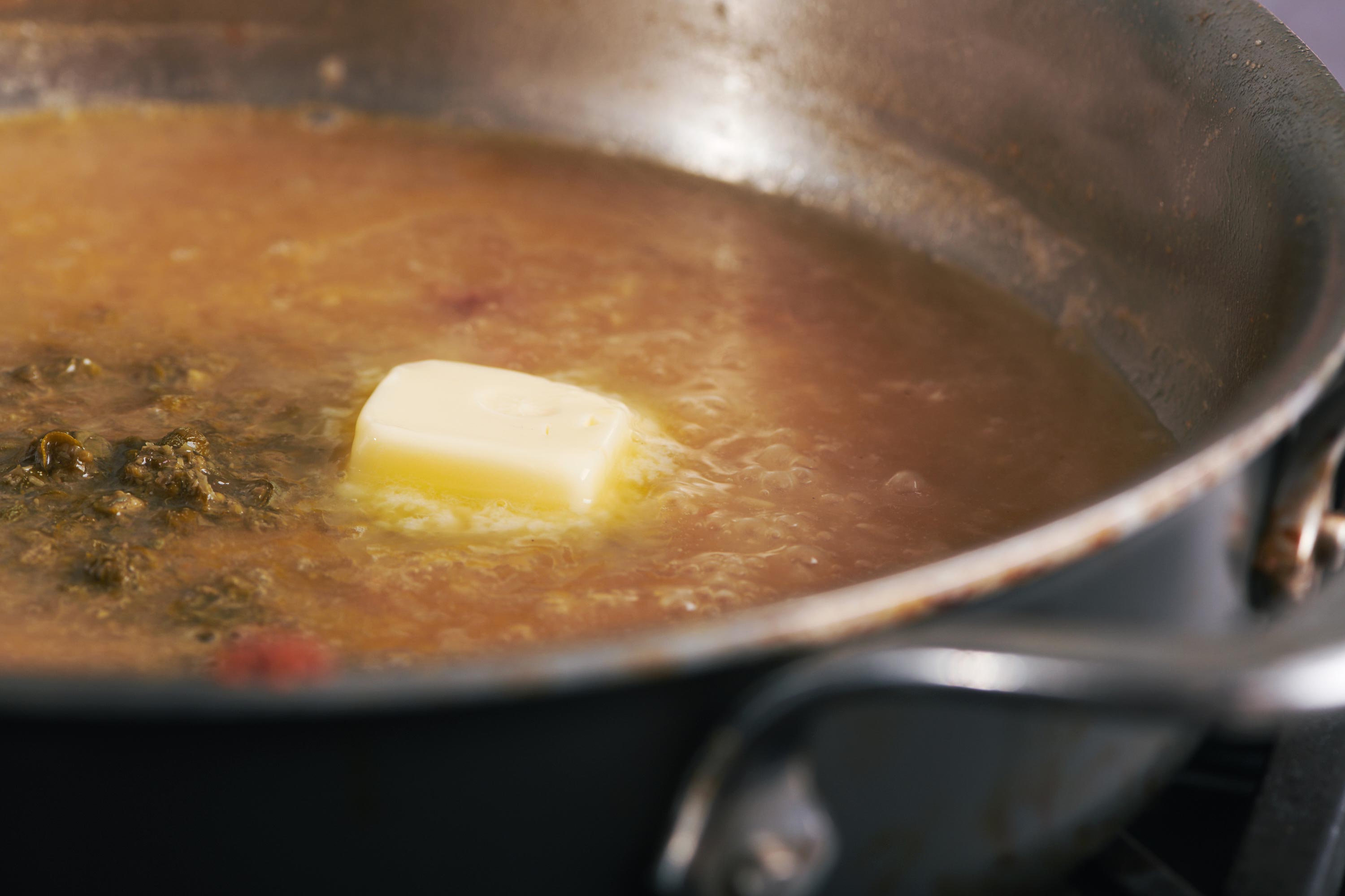 Butter melting in a skillet of sauce.