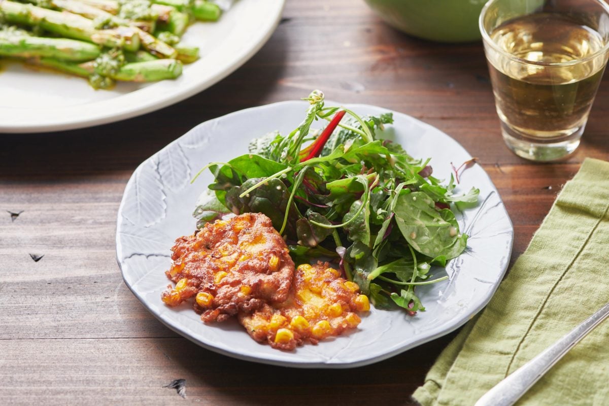 Corn and Zucchini Fritters on a plate with salad.