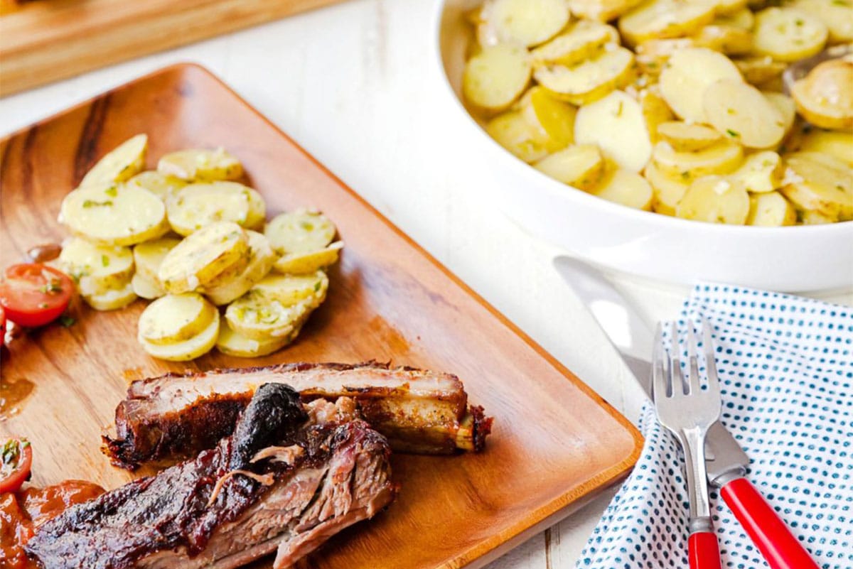 French potato salad and barbecued ribs on plates.