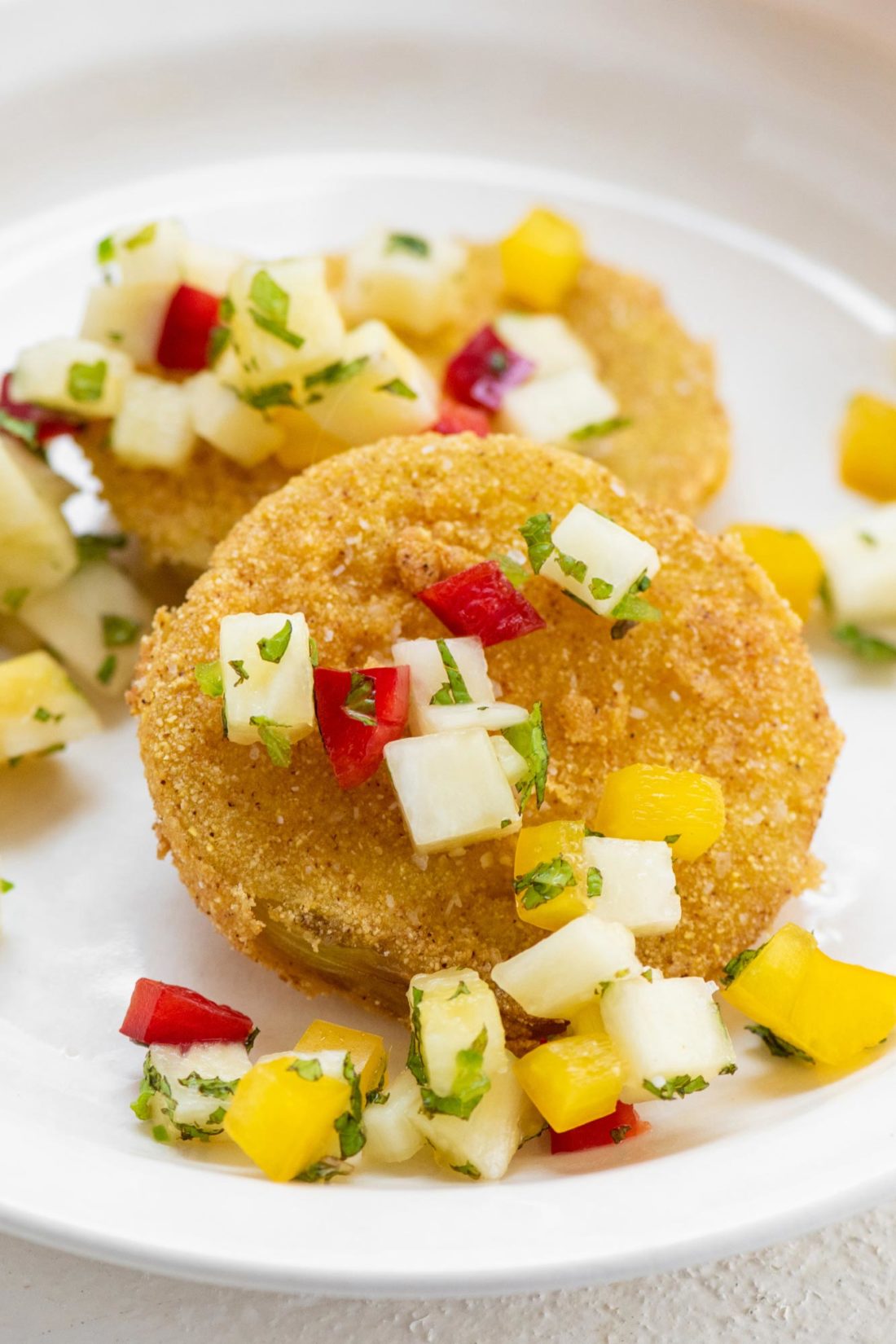 Fried Green Tomatoes topped with Pineapple Mint Salsa on a plate.