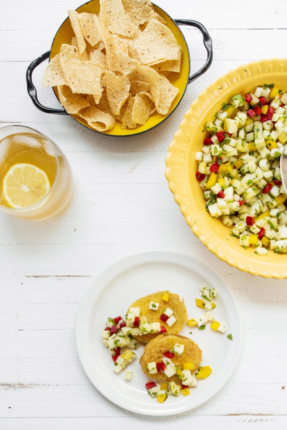 Plate of Fried Green Tomatoes with Pineapple Mint Salsa on a table with chips.