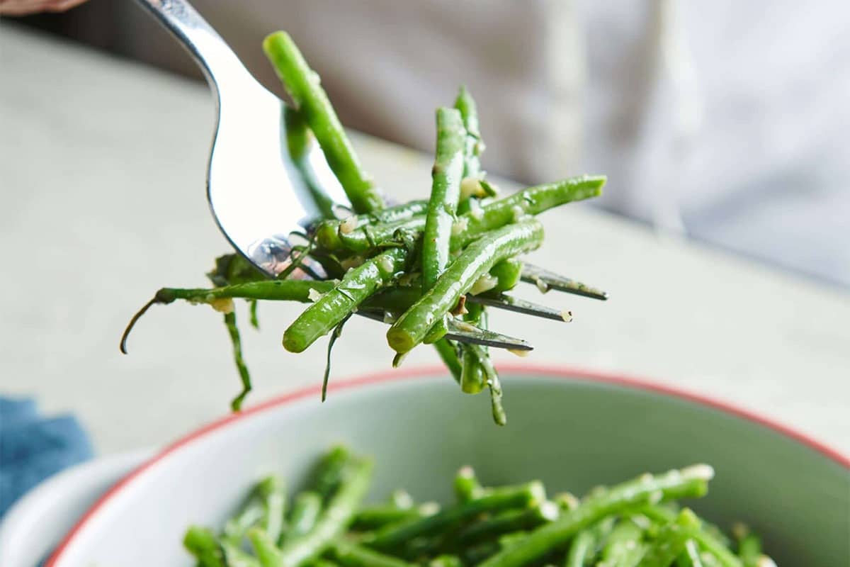 Fork grabbing Green Bean Nicoise Salad from a bowl.