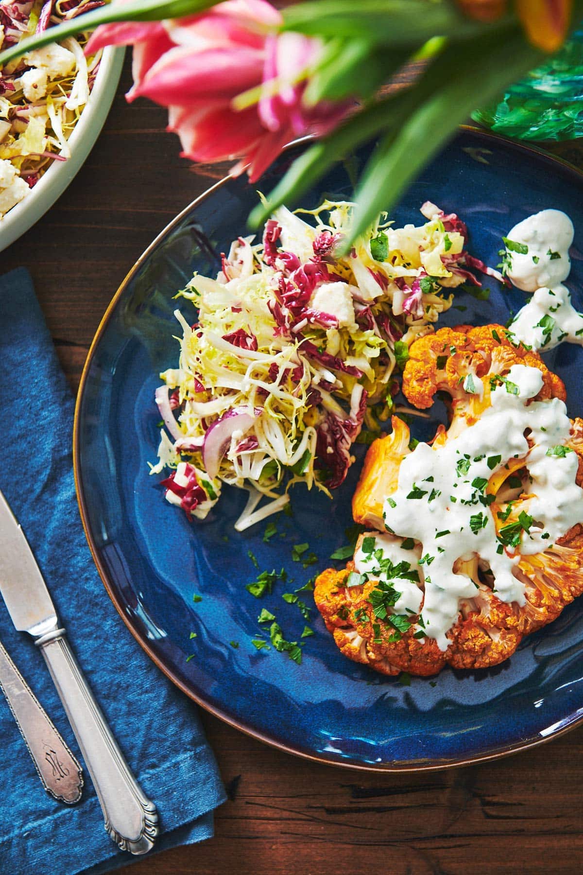 Salad and a Roasted Buffalo Cauliflower Steak on a blue plate.