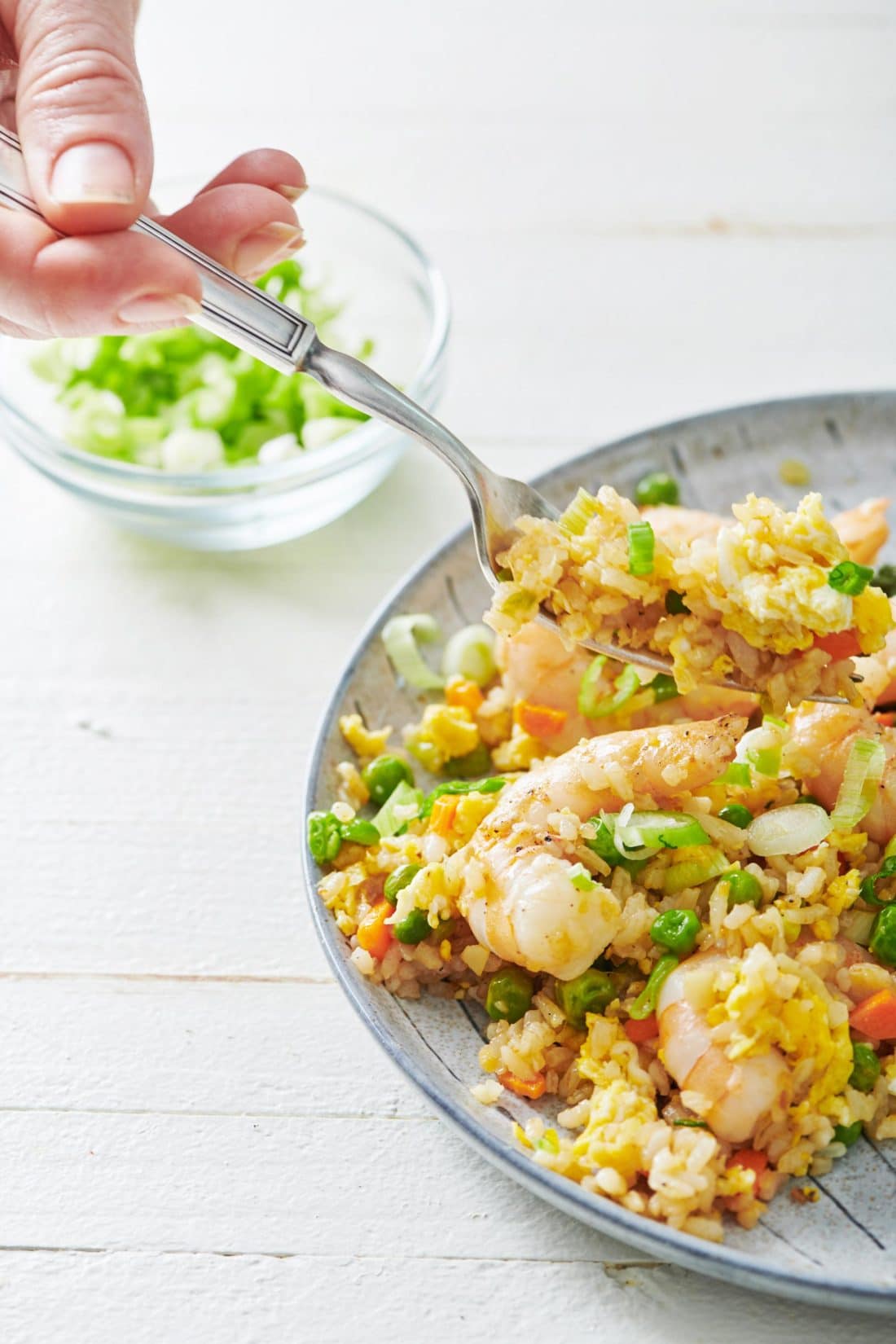 Fork scooping Shrimp Fried Rice from a plate.