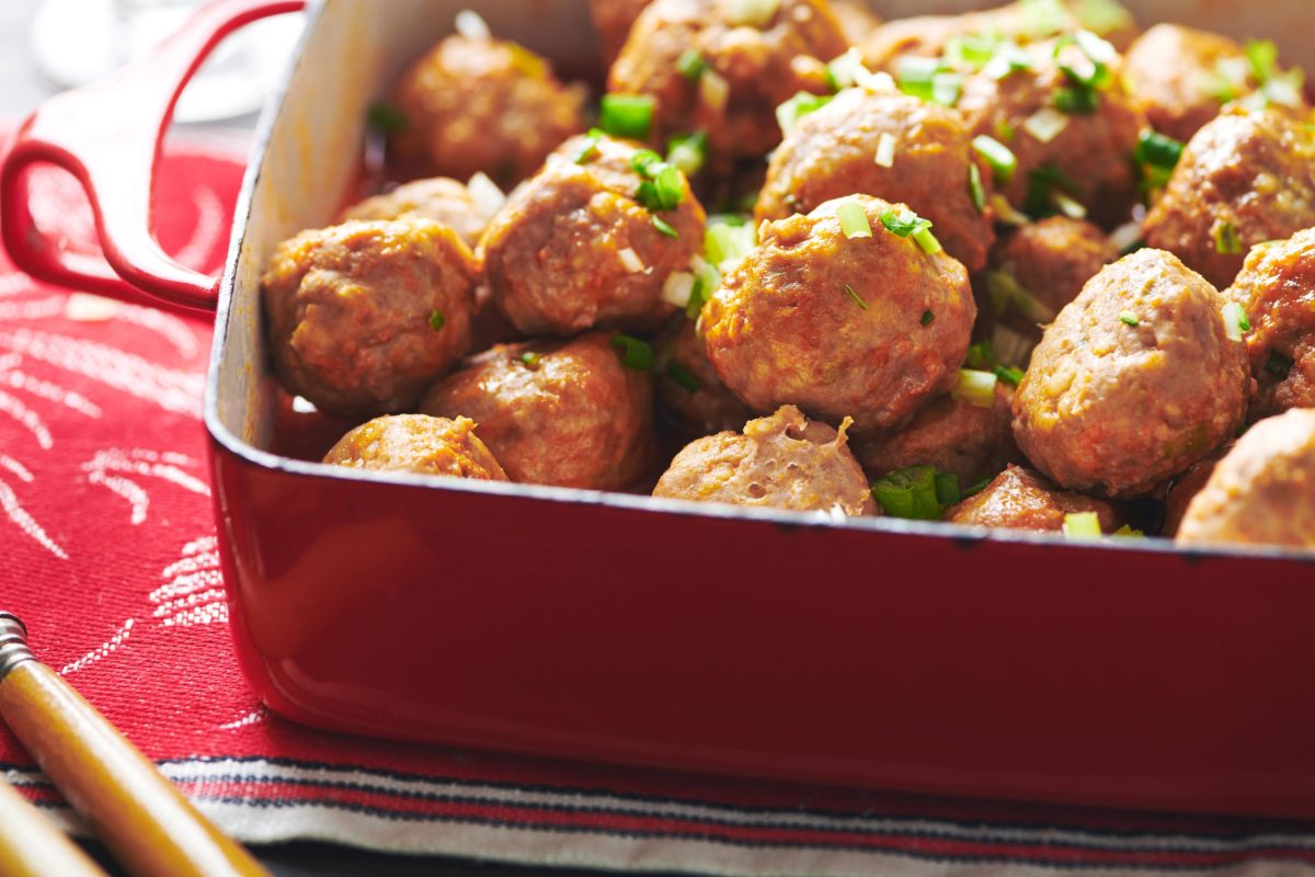  Buffalo Chicken Meatballs piled high in a red baking dish.