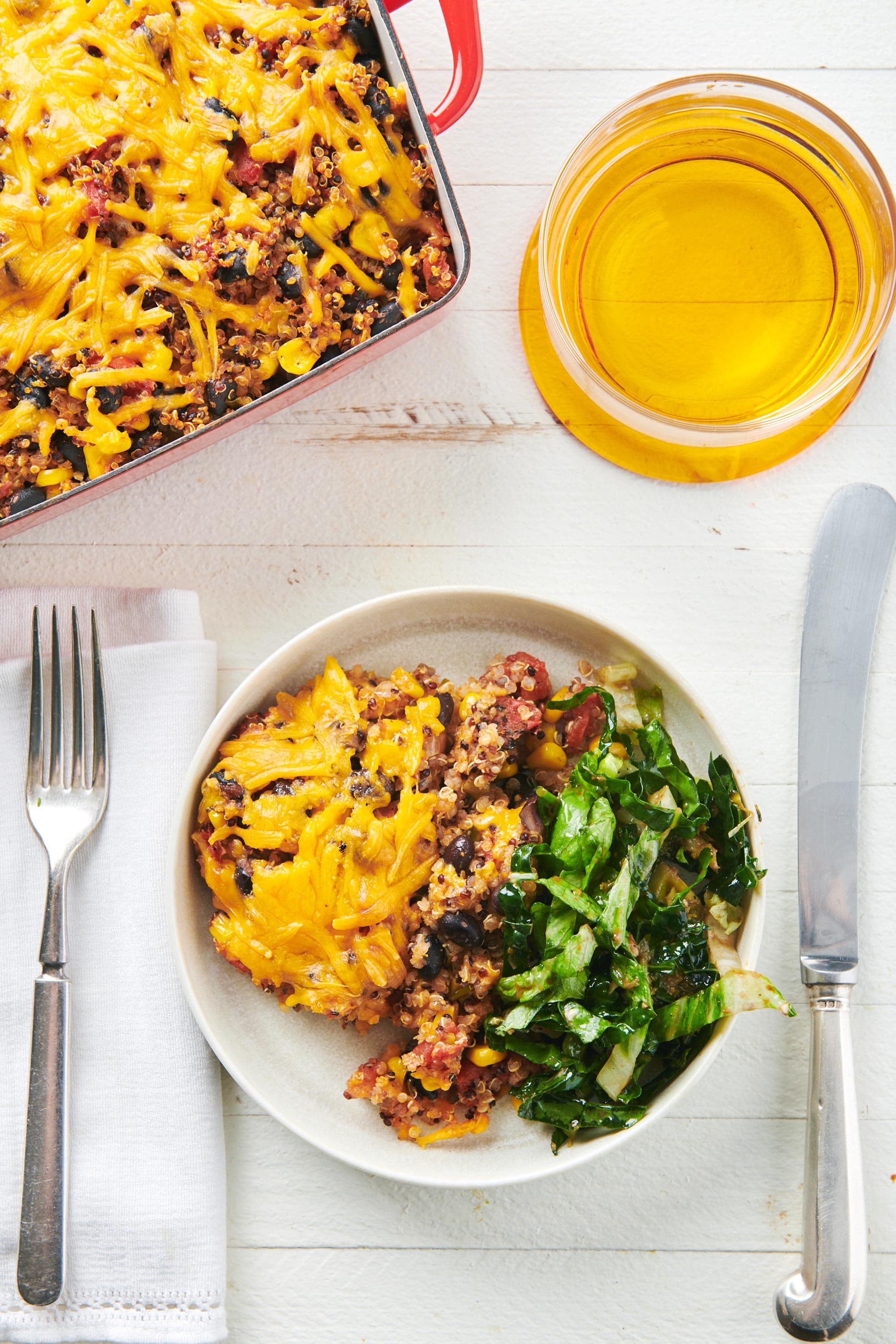 Southwest Quinoa Casserole on plate and in baking dish on white table with drink.
