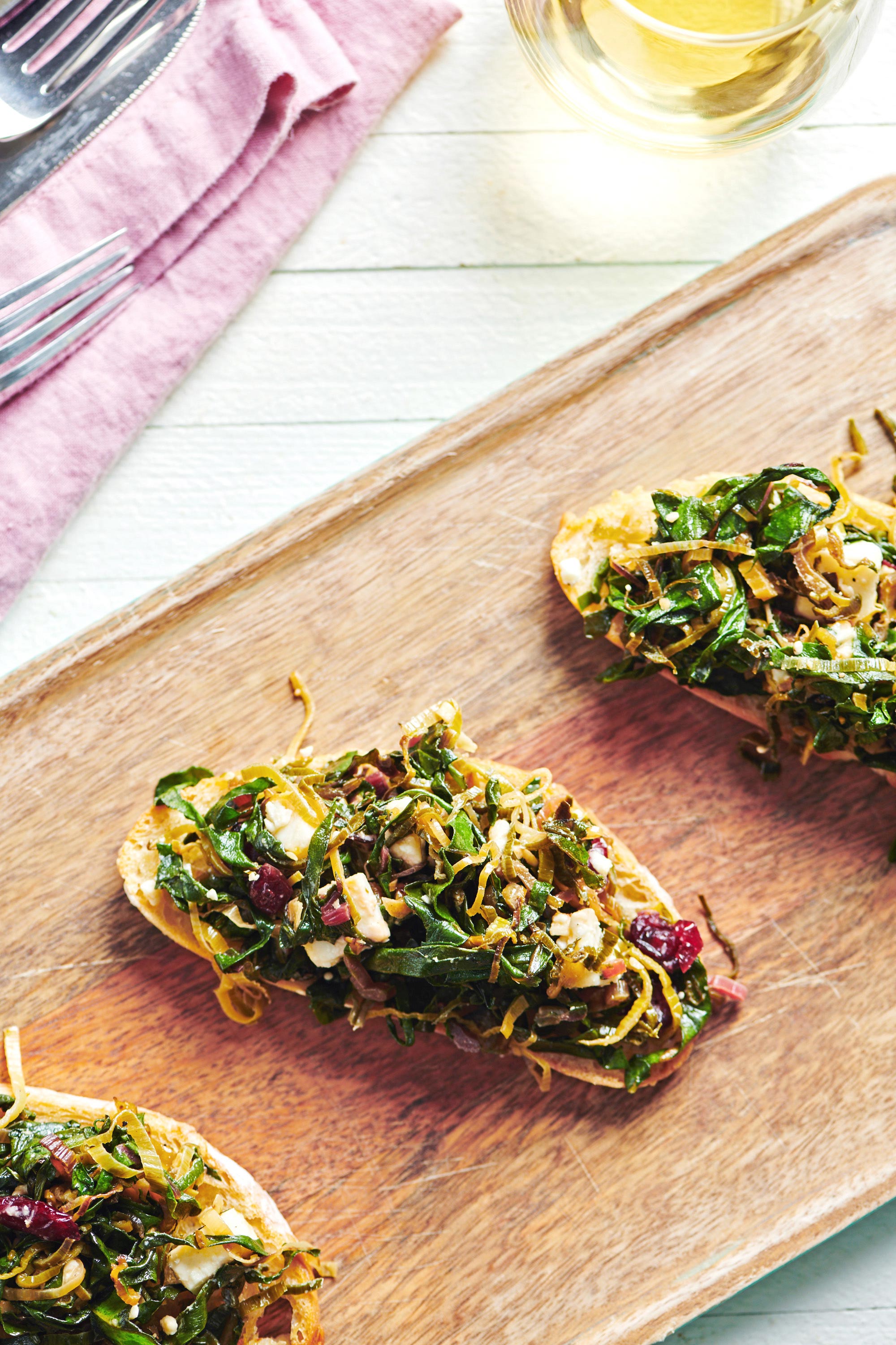 Three pieces of bruschetta topped with Swiss chard, leeks, and feta.