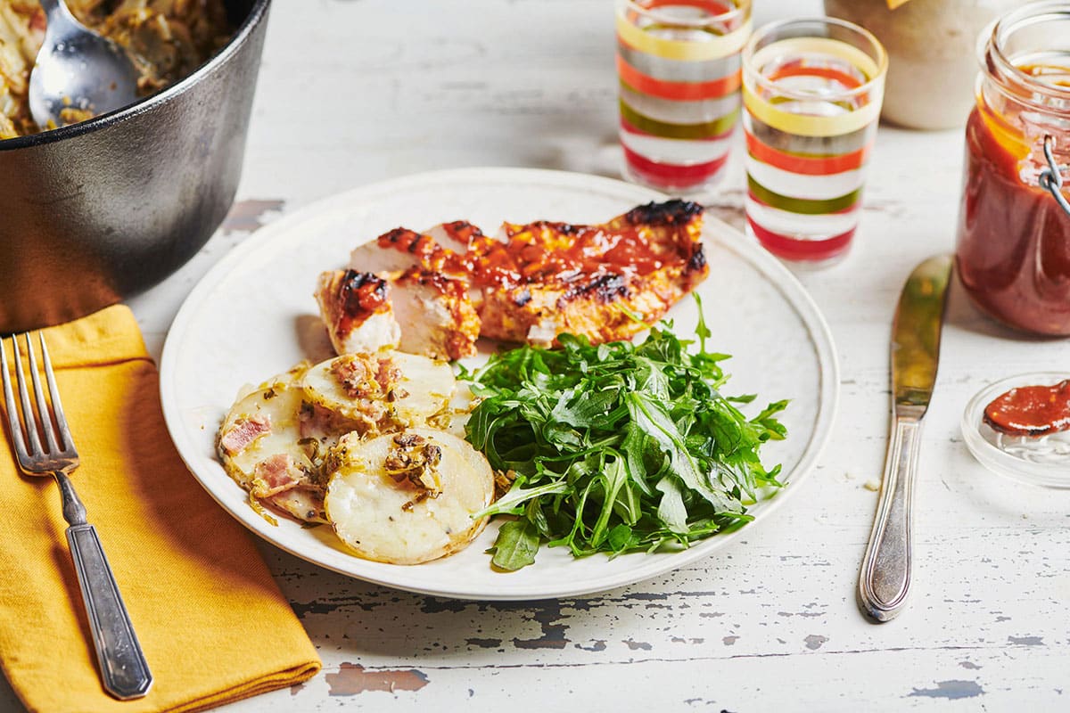 Dutch Oven Idaho Potatoes on a plate with greens and meat.