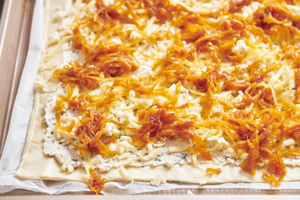 Caramelized Onions on an uncooked Four Cheese Pizza.
